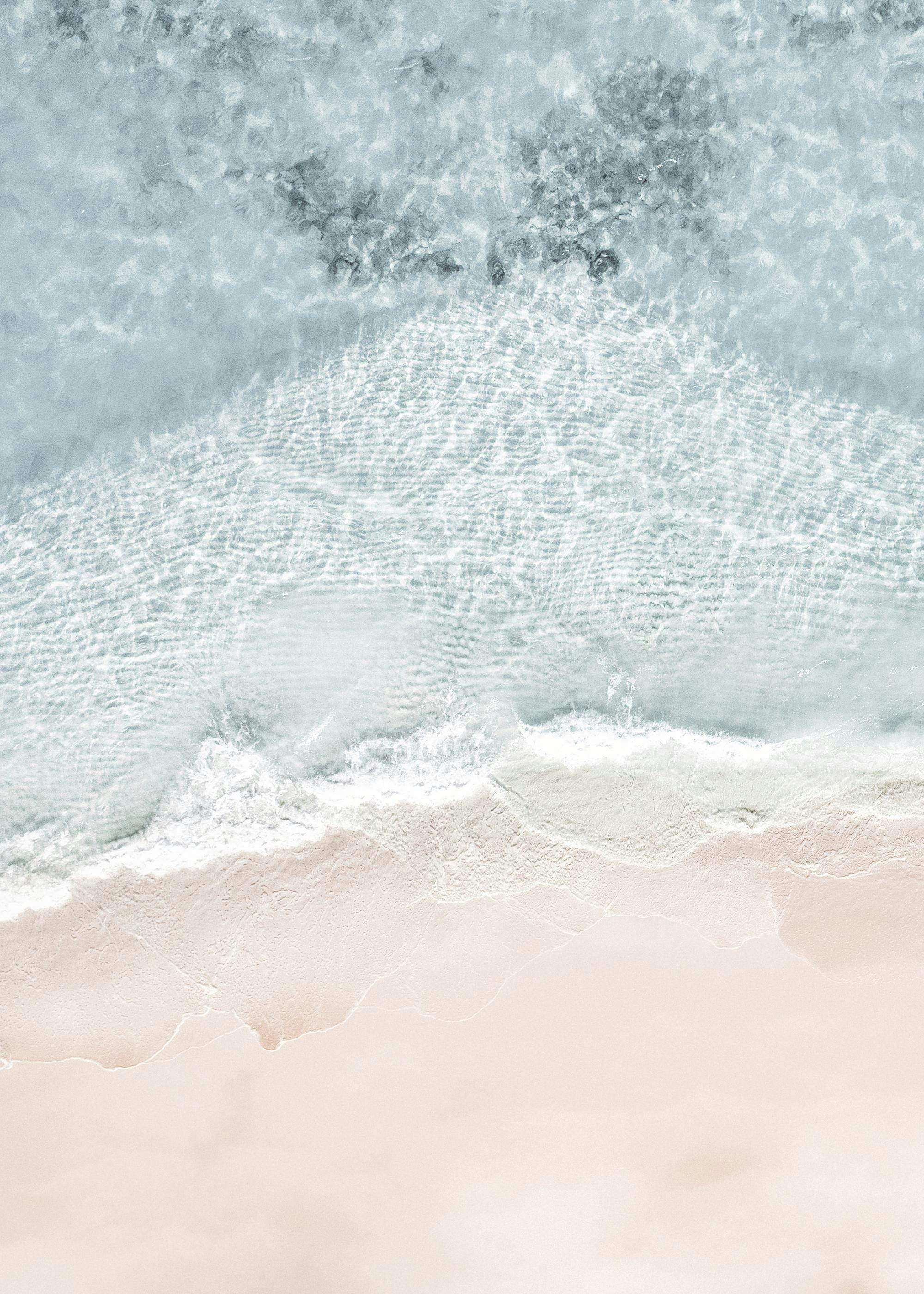 Póster de olas de mar turquesa rompiendo en una playa de arena dorada desde vista aérea.