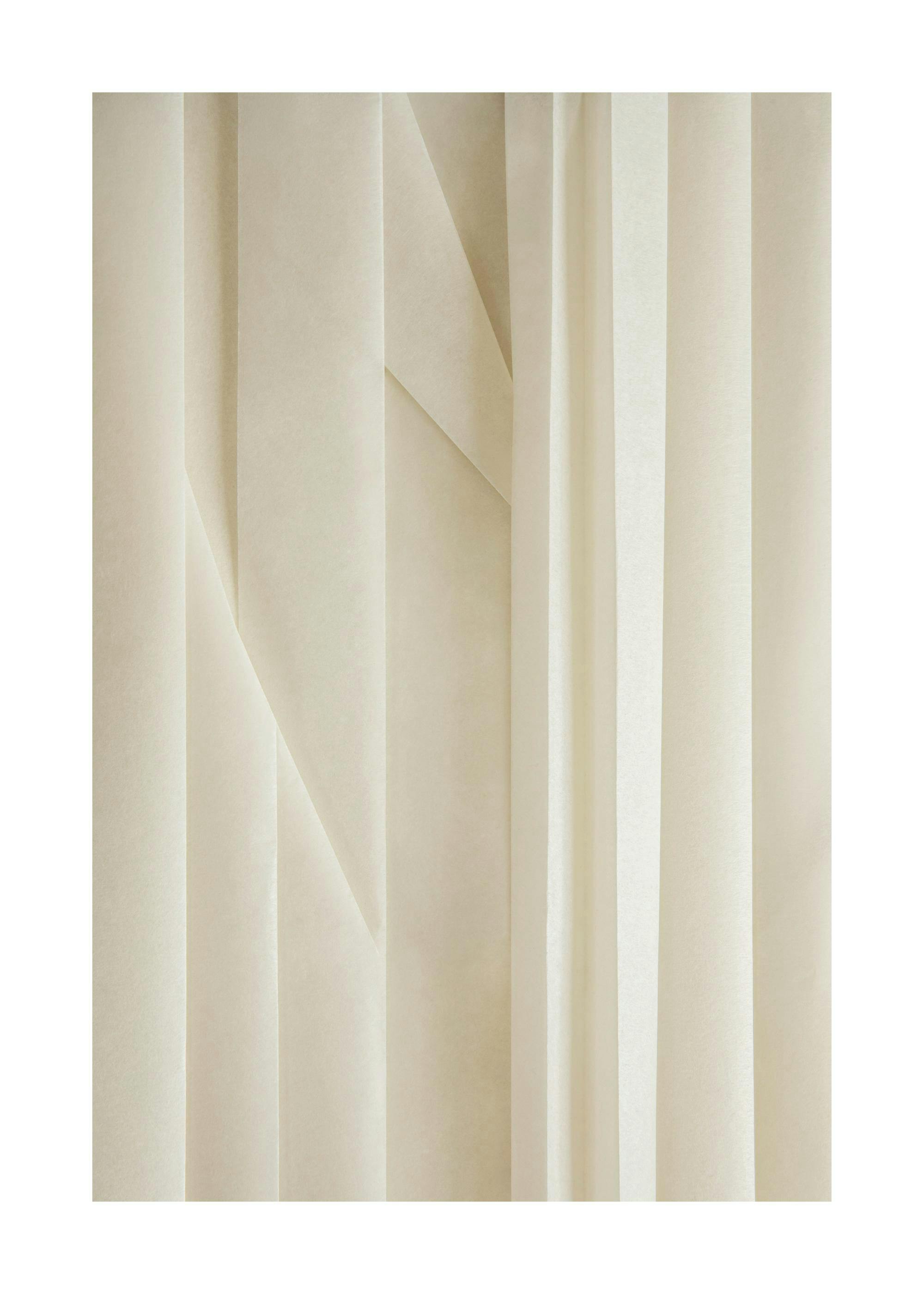 Fotografía de primer plano de la textura de papel de arroz doblado en tonos crema, mostrando pliegues y sombras.