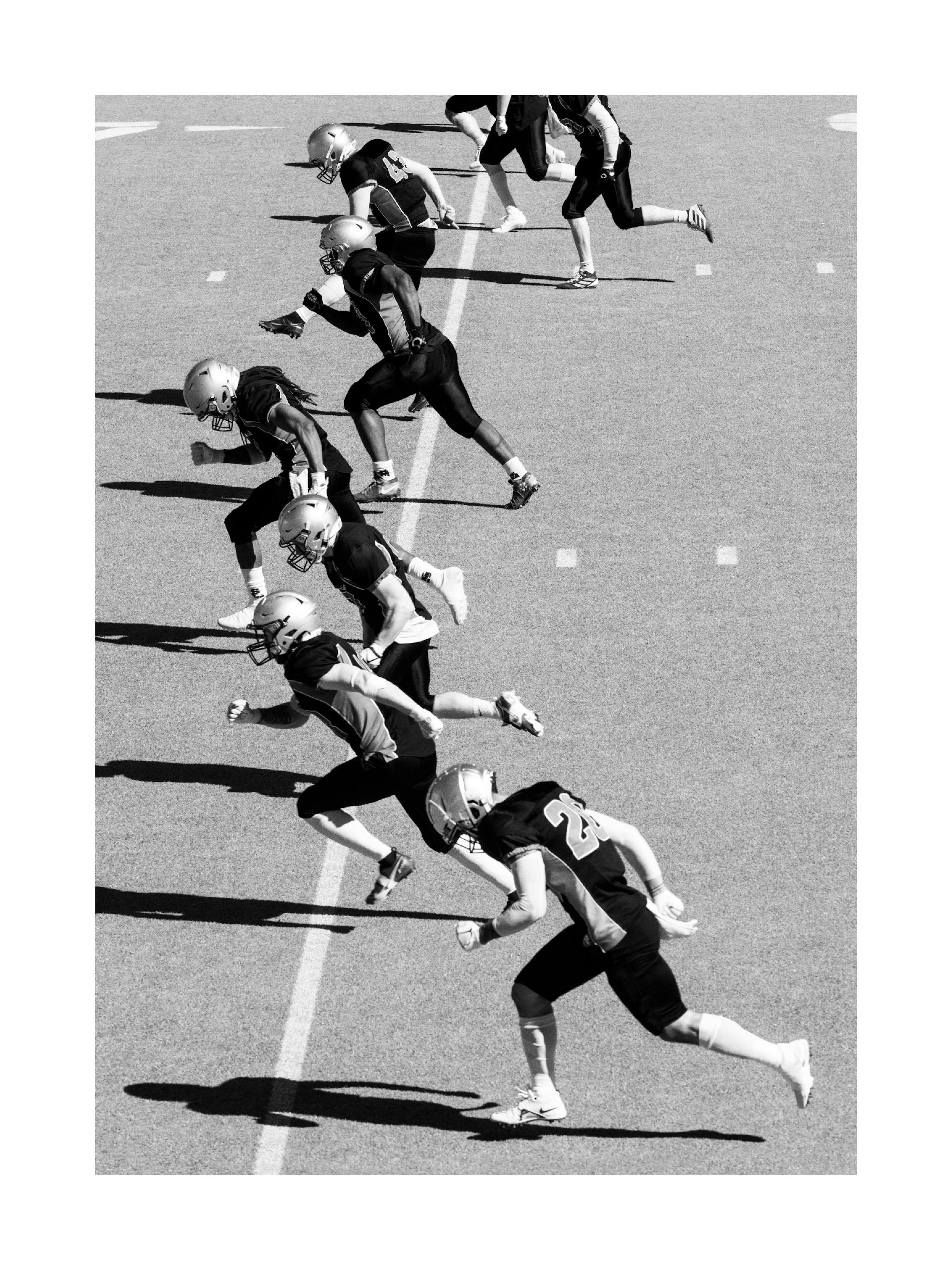 Fotografia in bianco e nero di giocatori di football americano che corrono in campo, poster sportivo, lavoro di squadra