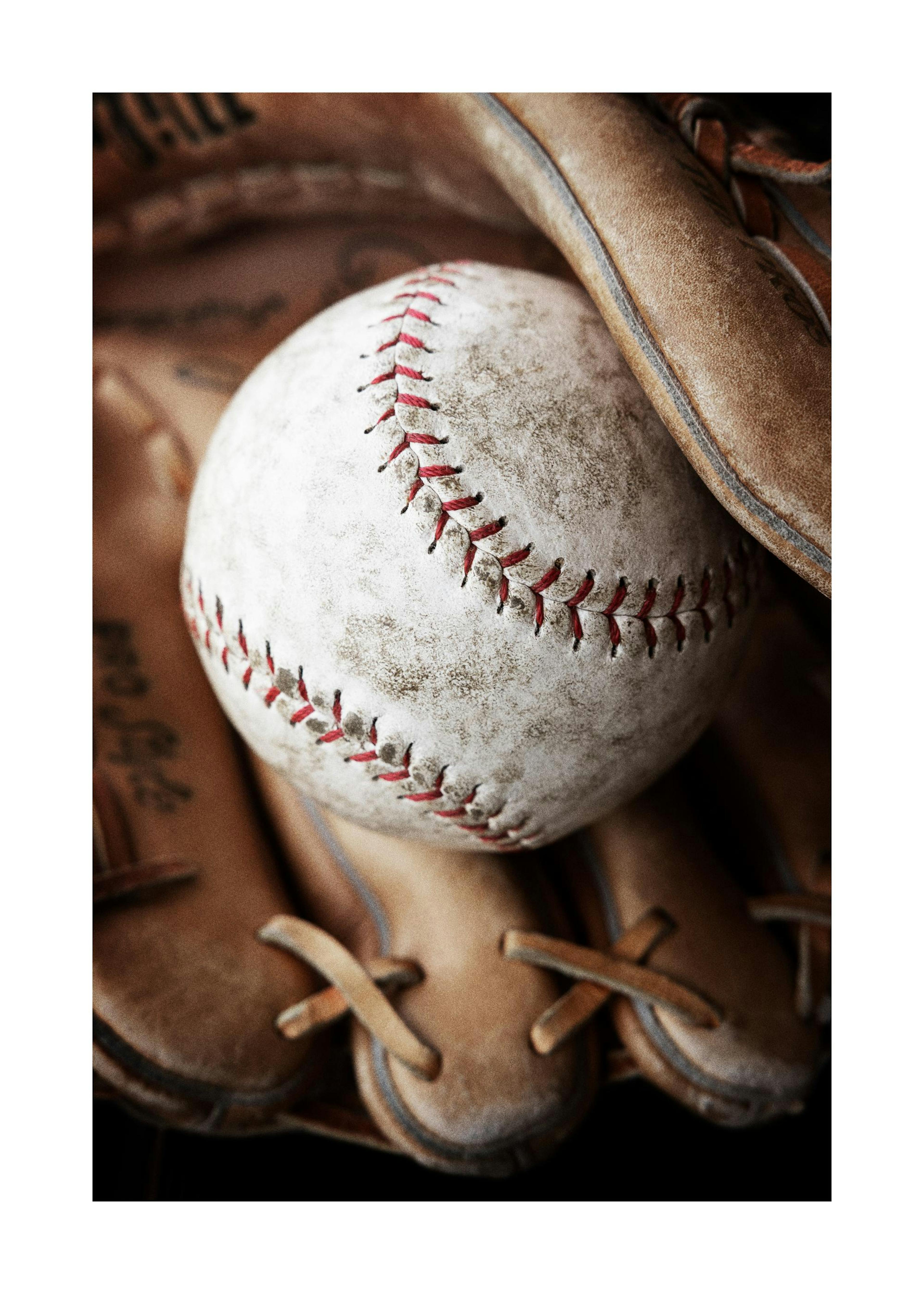 Béisbol sucio con costuras rojas en un guante de béisbol de cuero desgastado, con efecto granulado.