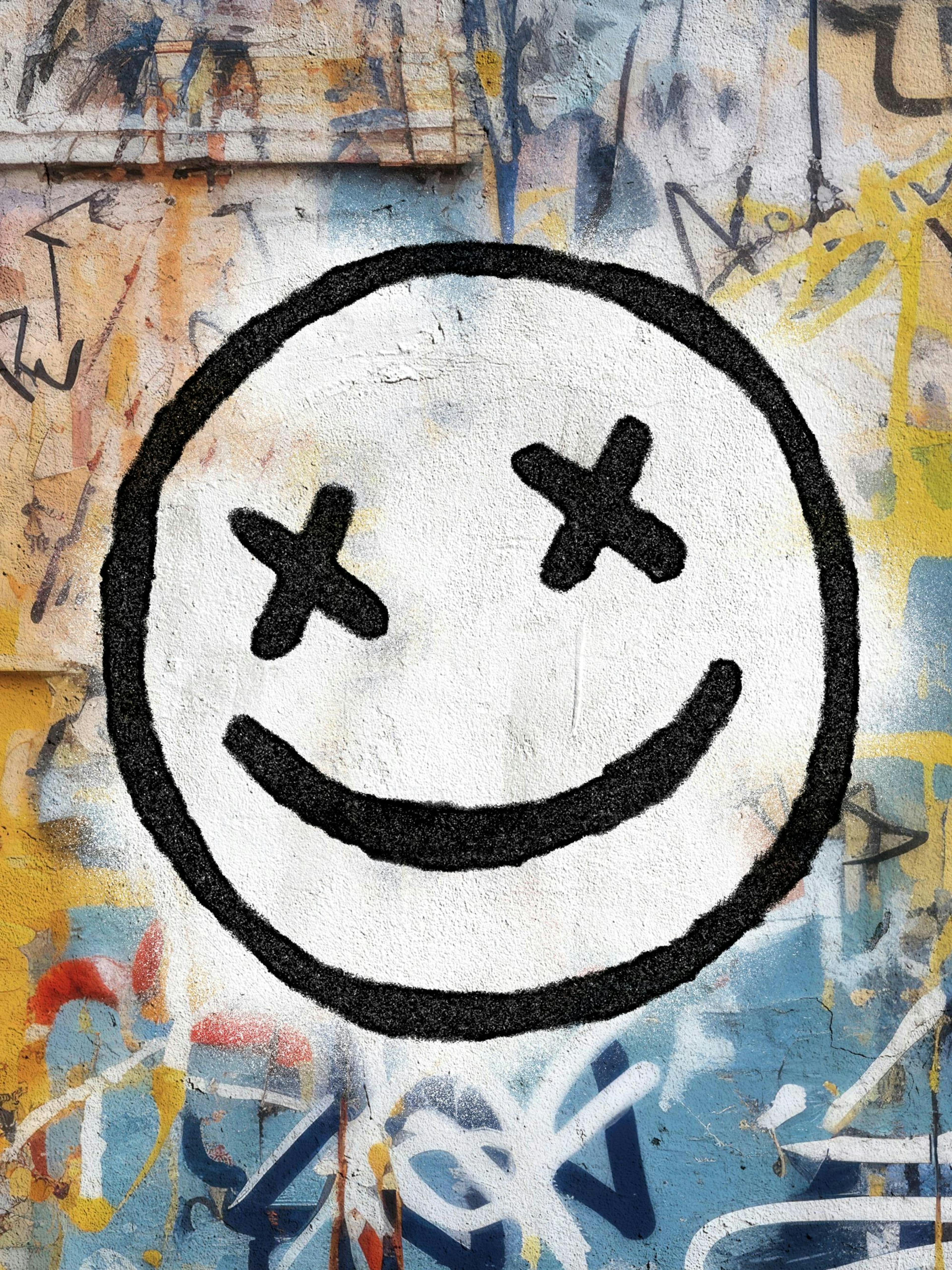 Graffiti plakát s bílým smajlíkem a křížovými očima na barevném street art pozadí.