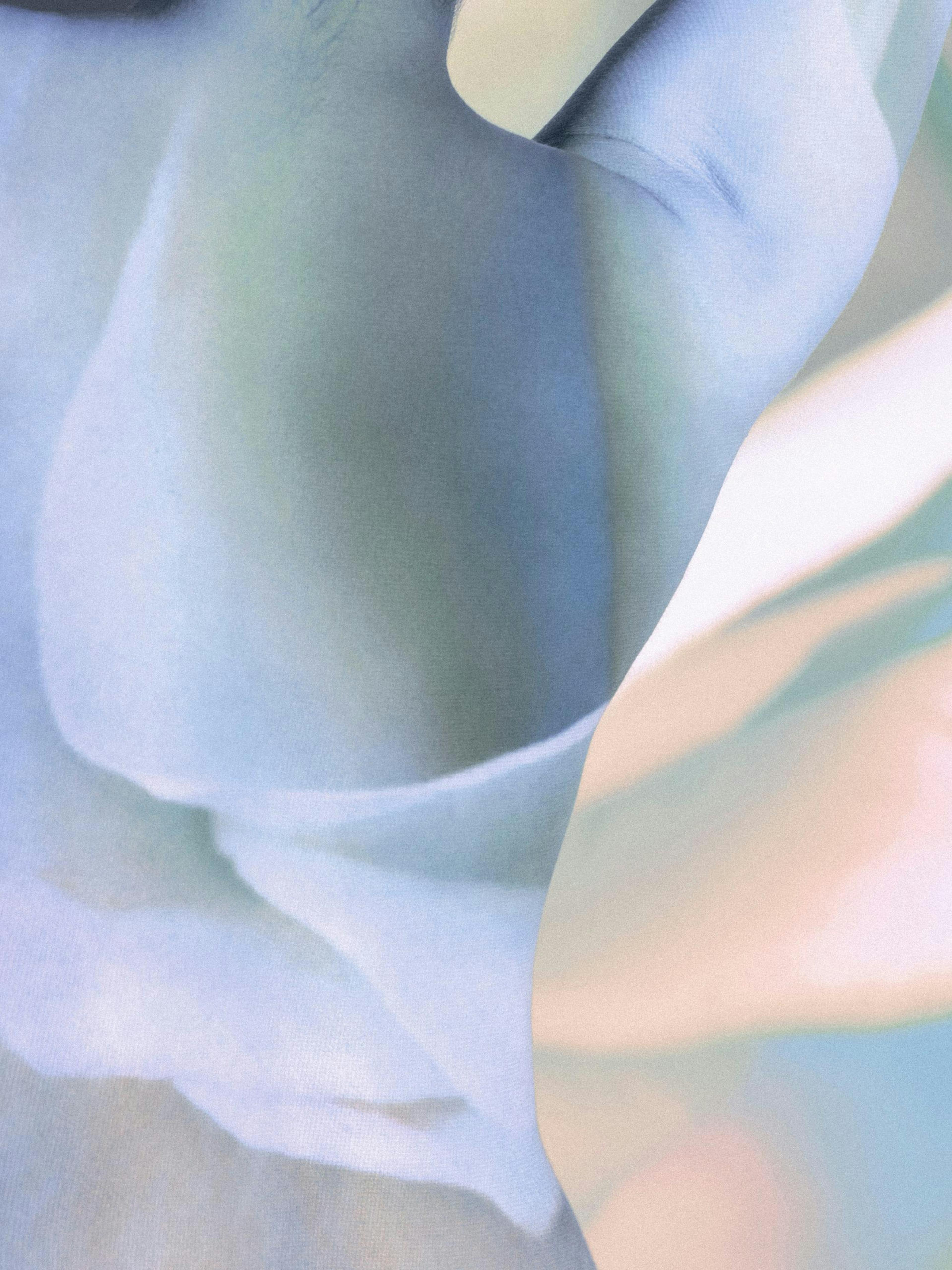 Abstract art print of soft, flowing fabric in blue, green, and peach tones with a grainy texture creating an ethereal feel.