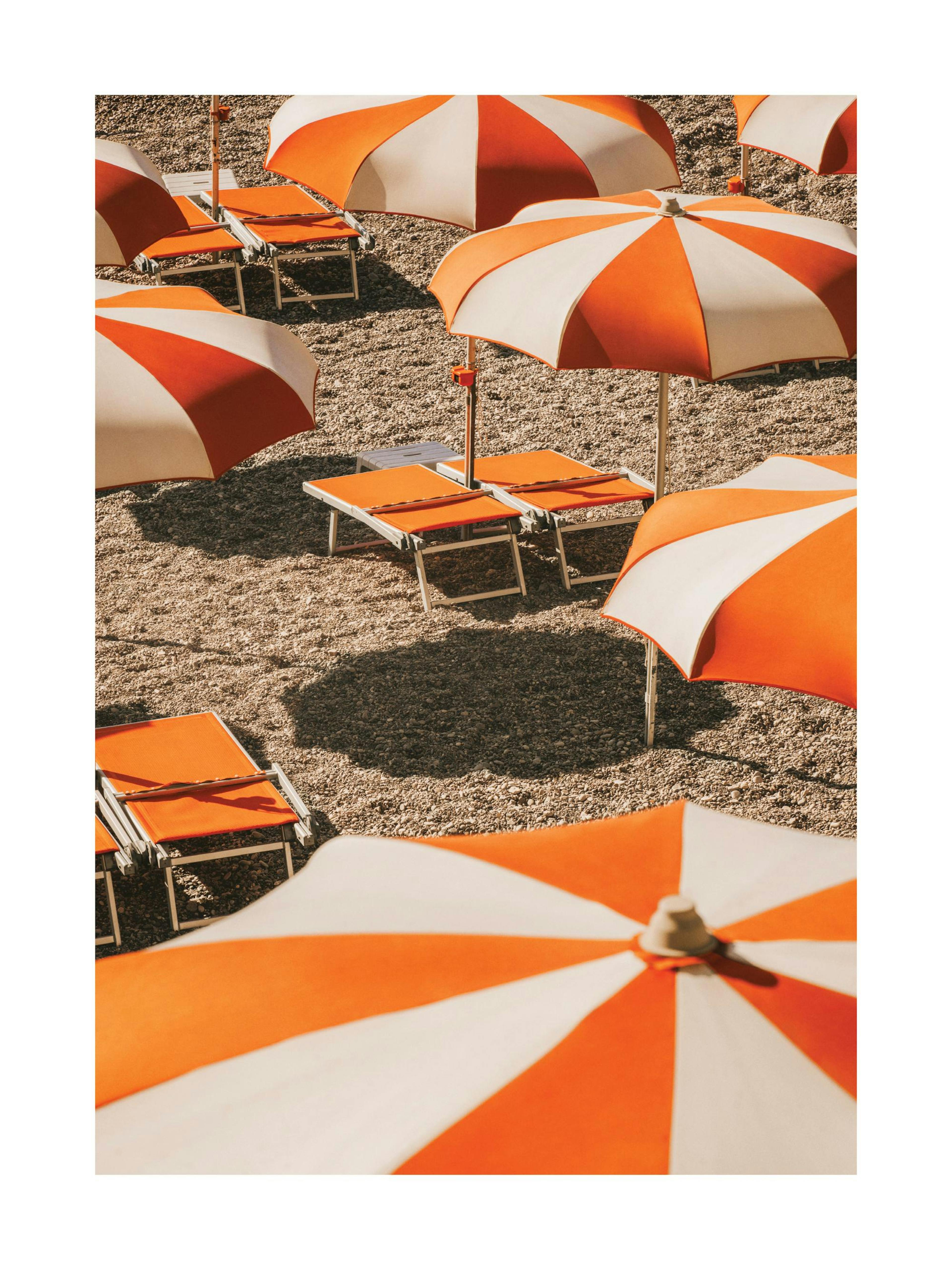 Plakat przedstawia plażę z pomarańczowo-białymi parasolami i leżakami, oddającą klimat Wybrzeża Amalfi.