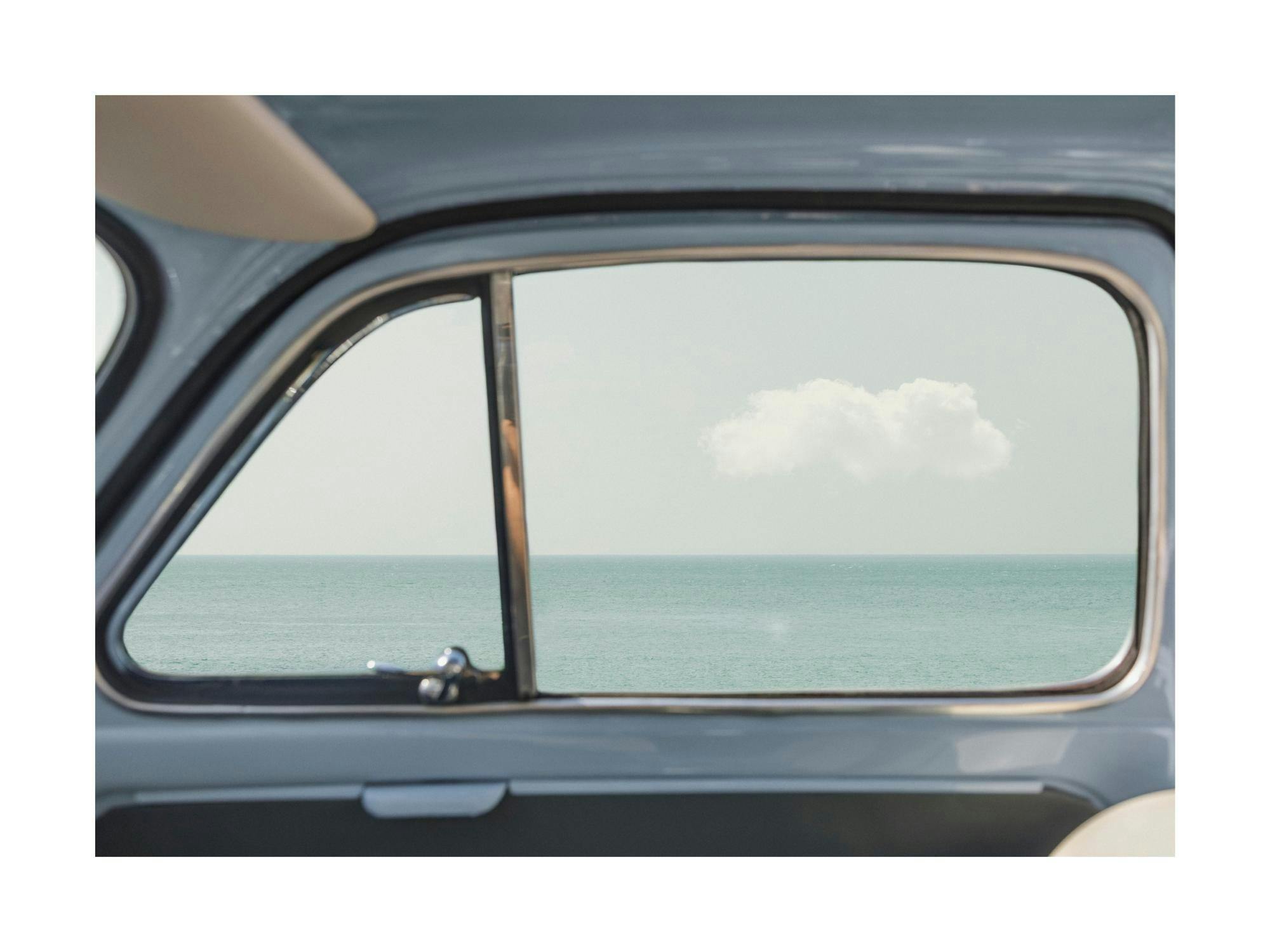 Fotoposter av havsutsikt från ett bilfönster med en ensam molntuss på himlen, fridfull bilresa.