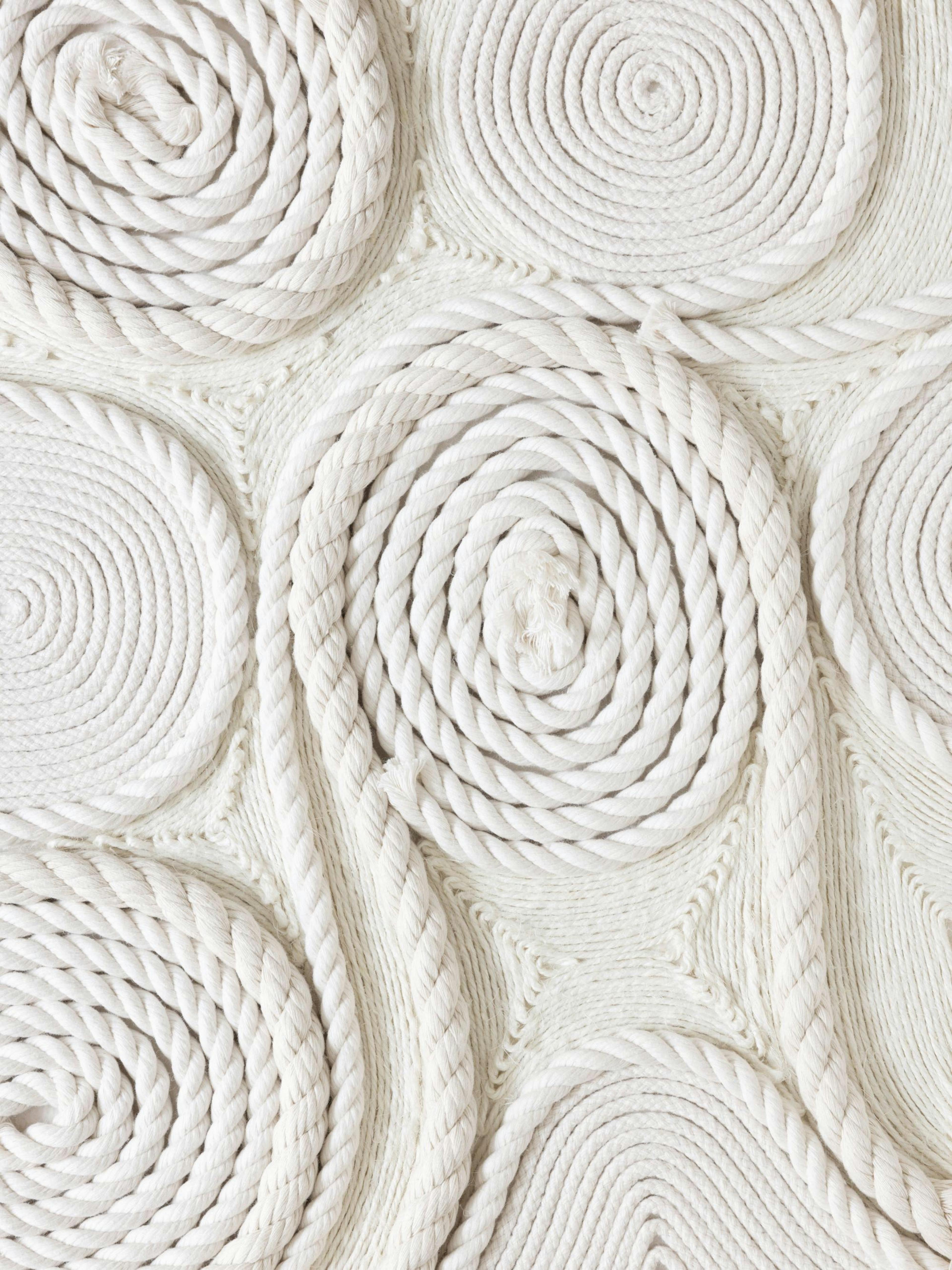 White ropes coiled into tight and loose spirals creating a unique textured pattern on a light background print.