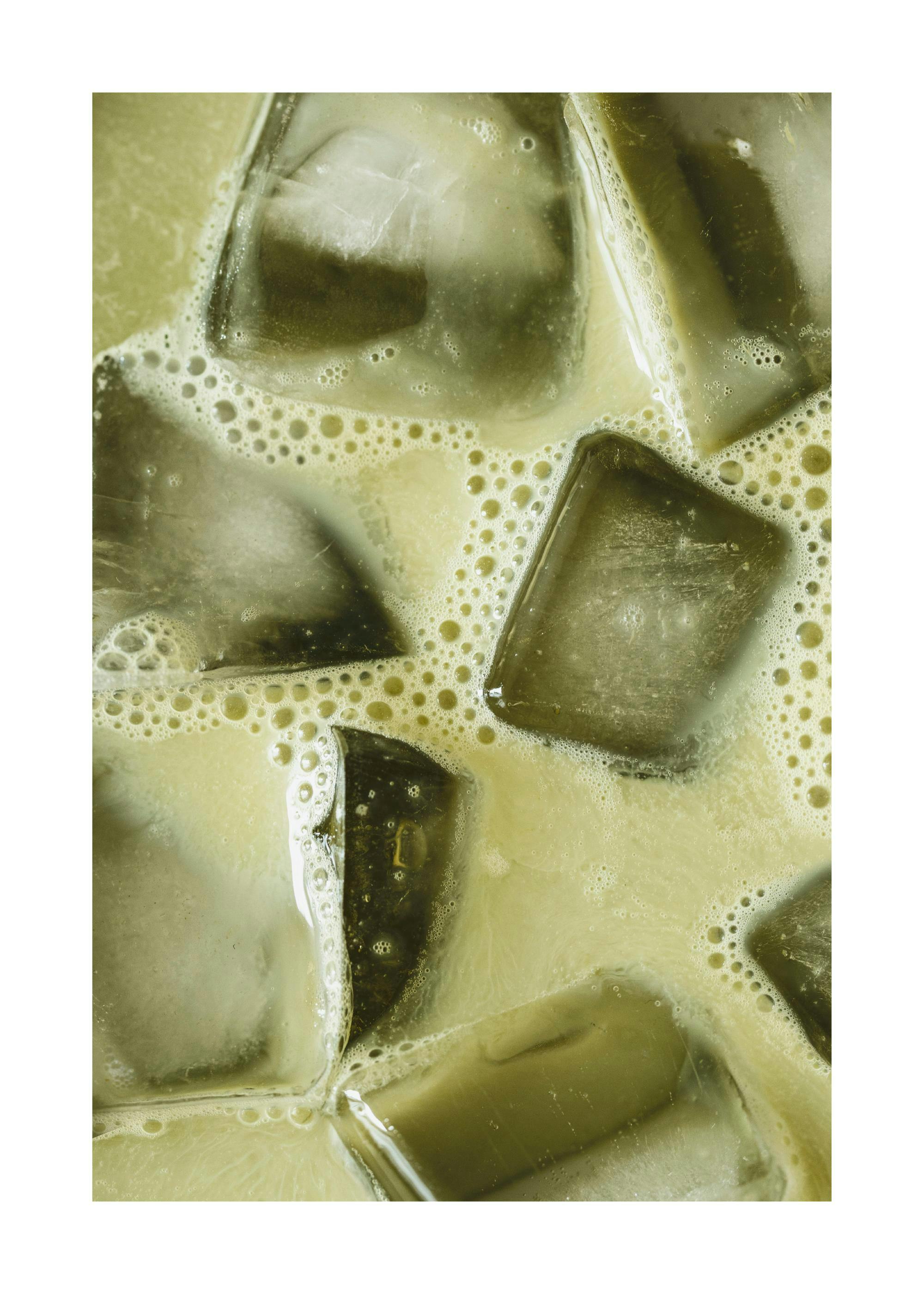 Gedetailleerde close-up van een matcha latte met ijsblokjes en schuim, een verfrissende drank