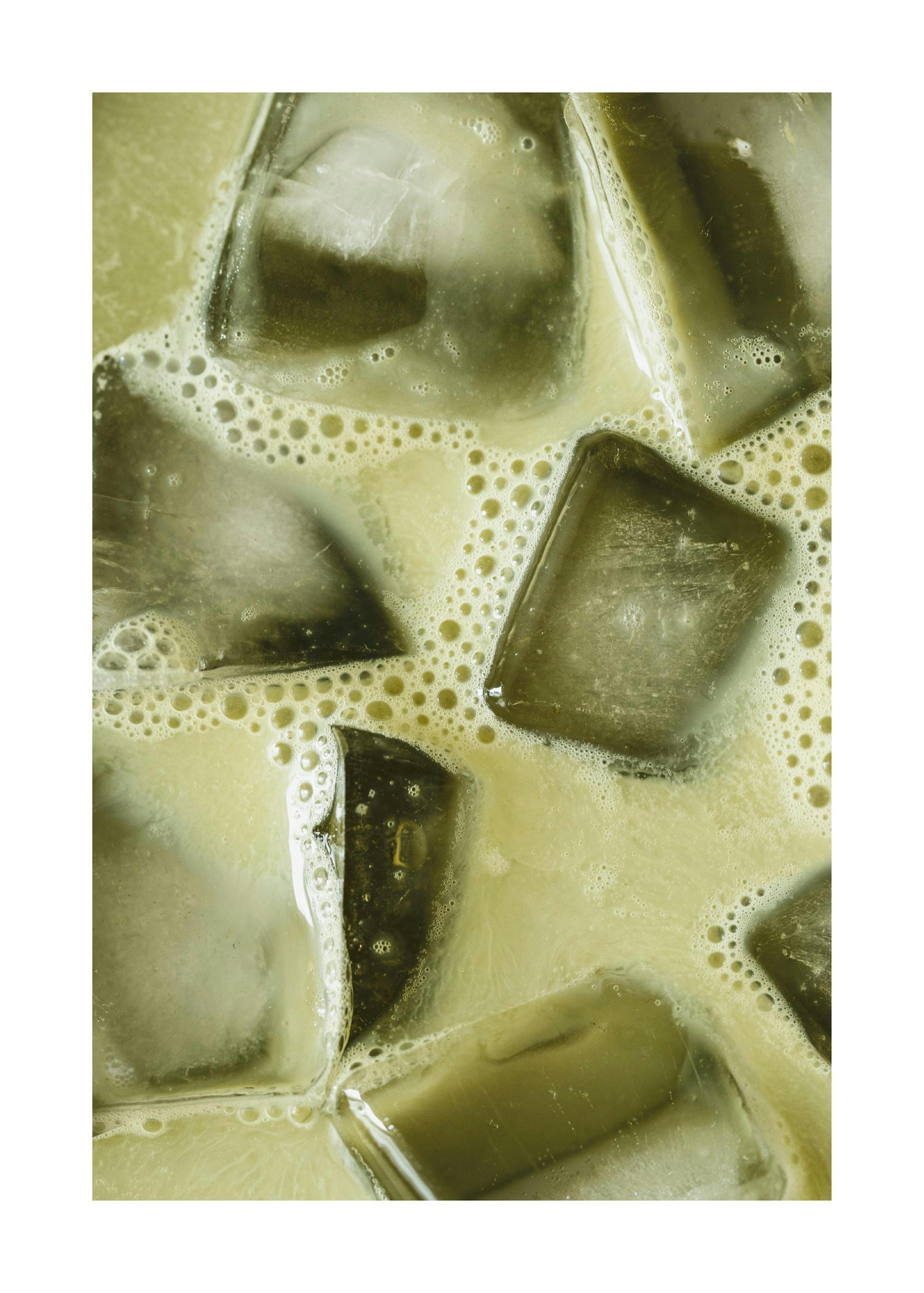 Close-up of an iced matcha latte with ice cubes and foam, kitchen poster print.