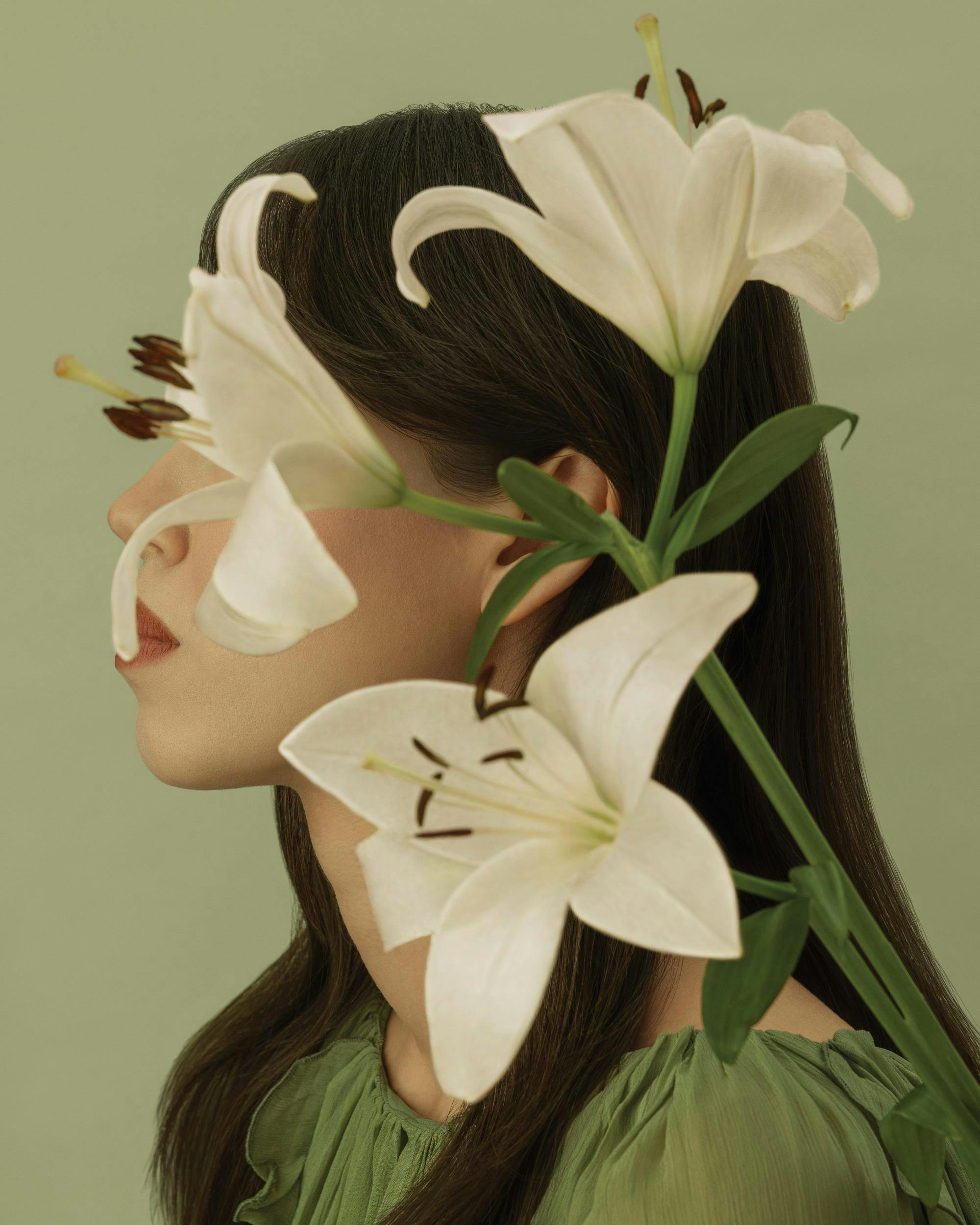En poster som visar en kvinnas ansikte i profil, delvis skymt av vita liljor, med gröna detaljer.