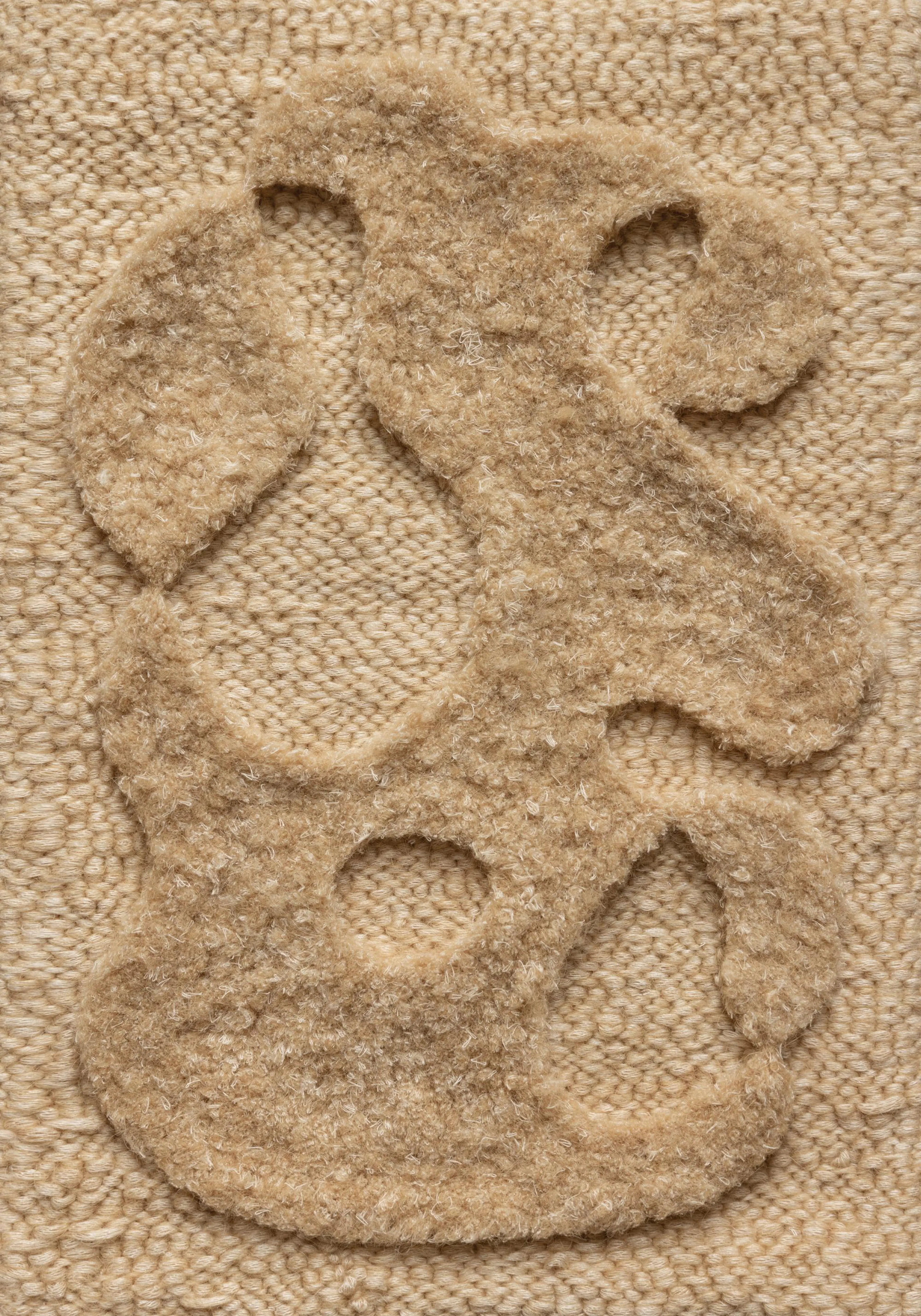 A beige and cream print featuring abstract organic shapes with a shaggy texture on a knitted background.