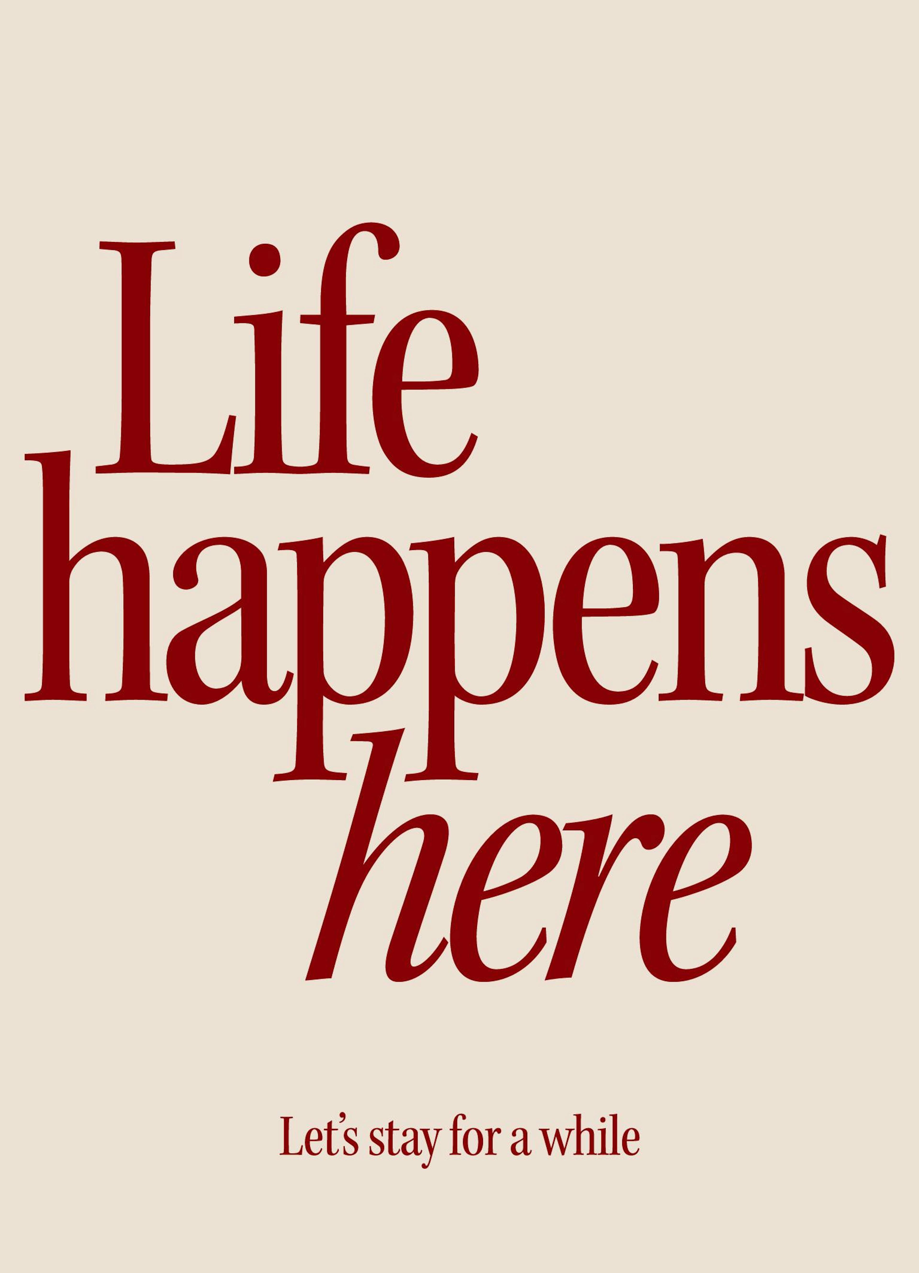 벽에 걸린 베이지색 Life happens here 문구 포스터와 원목 테이블 위 주전자, 책, 화병