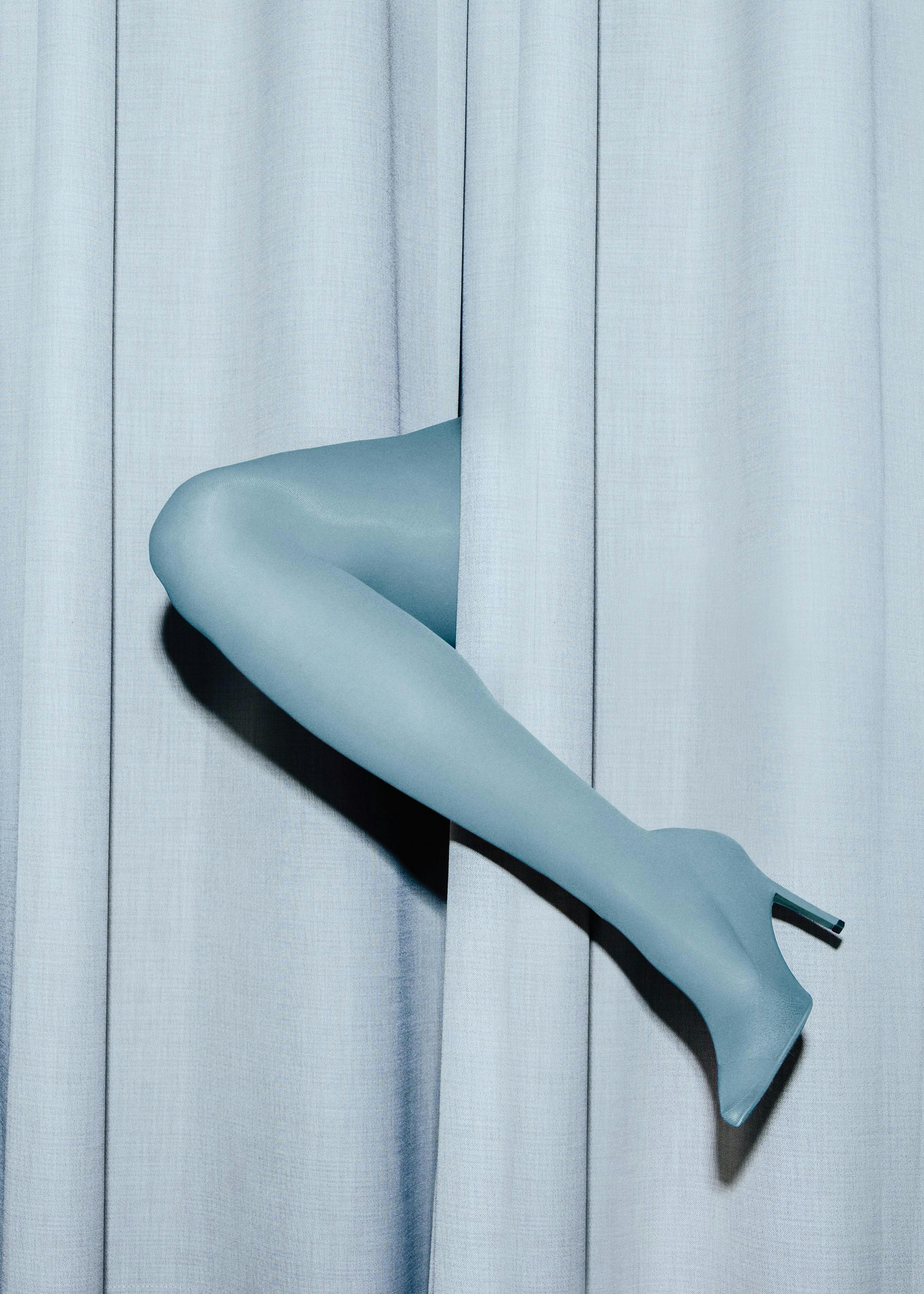 Póster de una pierna femenina azul claro con tacón asomándose por una cortina del mismo color.