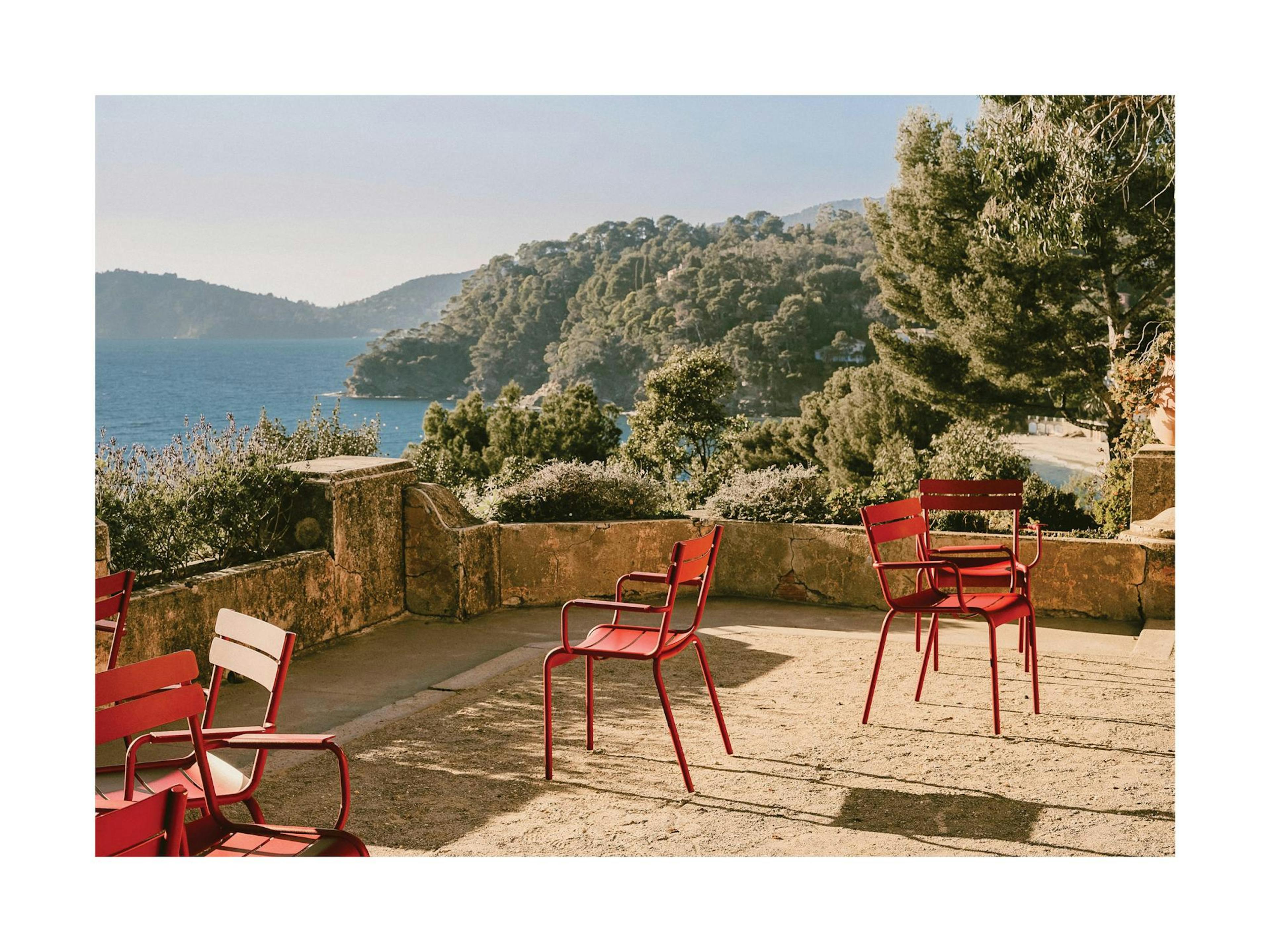 Thao Courtials Rayol Print: Mountain landscape photo with ocean view and red balcony chairs, capturing a tropical summer vibe.
