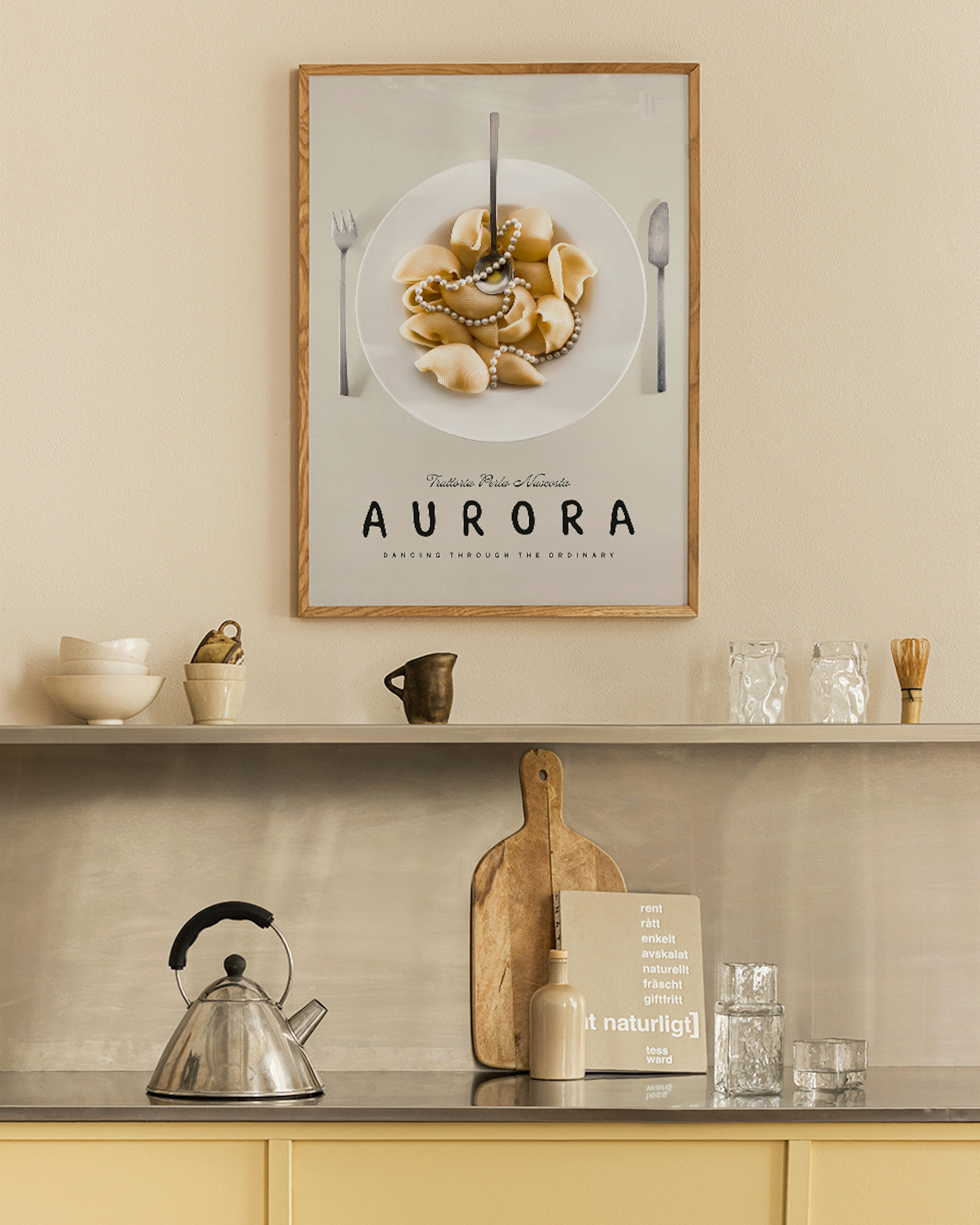 A pasta print with conchiglie pasta, a spoon, and pearl necklace on a white plate, displayed above a kitchen counter.