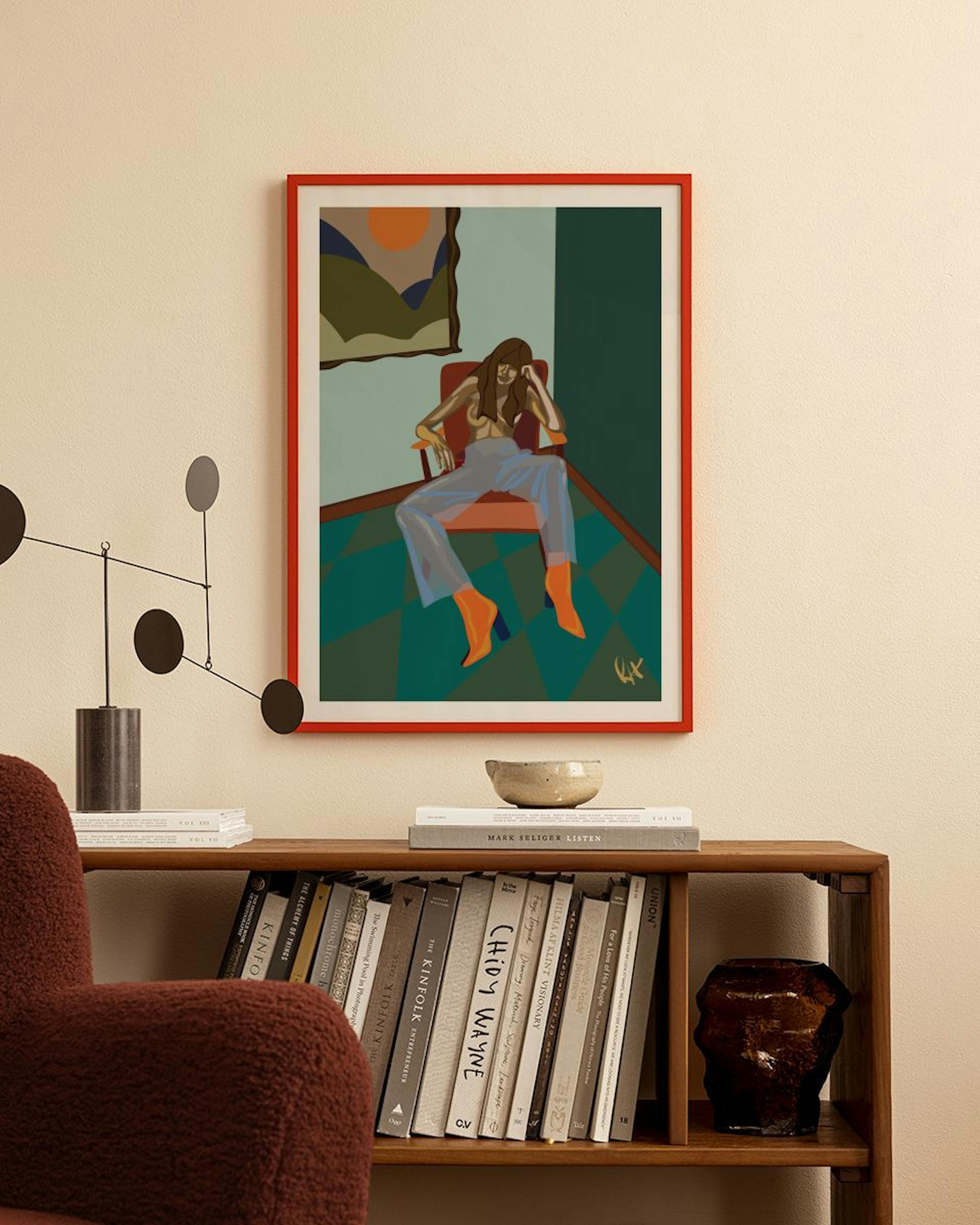 A print of a woman in a chair with orange boots, hanging above a wooden bookshelf in a modern room.