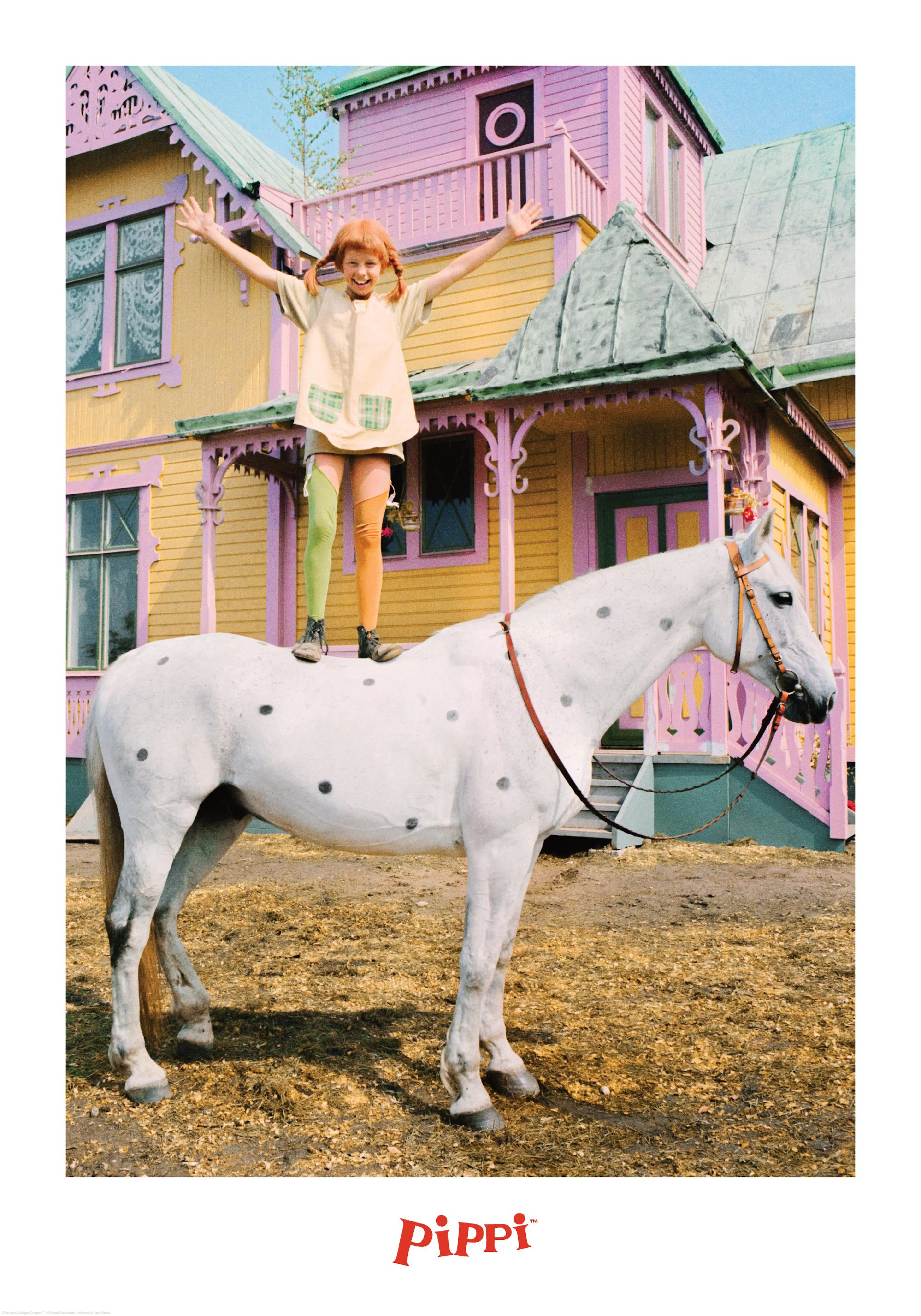 Pippi Calzaslargas feliz de pie sobre el caballo Pequeño Tío, con la Villa Villekulla al fondo.