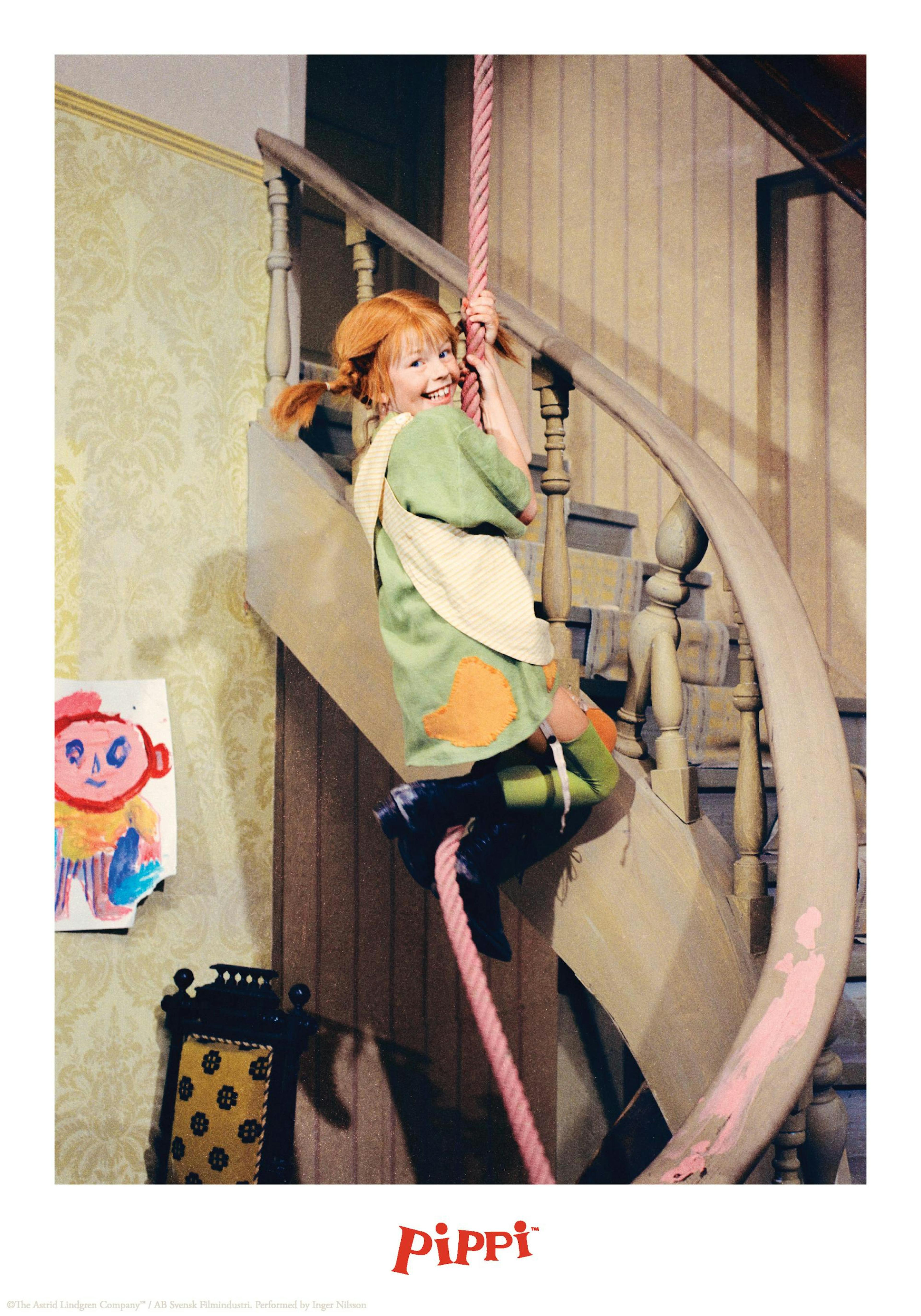 階段の手すりからロープでぶら下がる、おさげ髪の女の子が笑顔を見せるポスター。