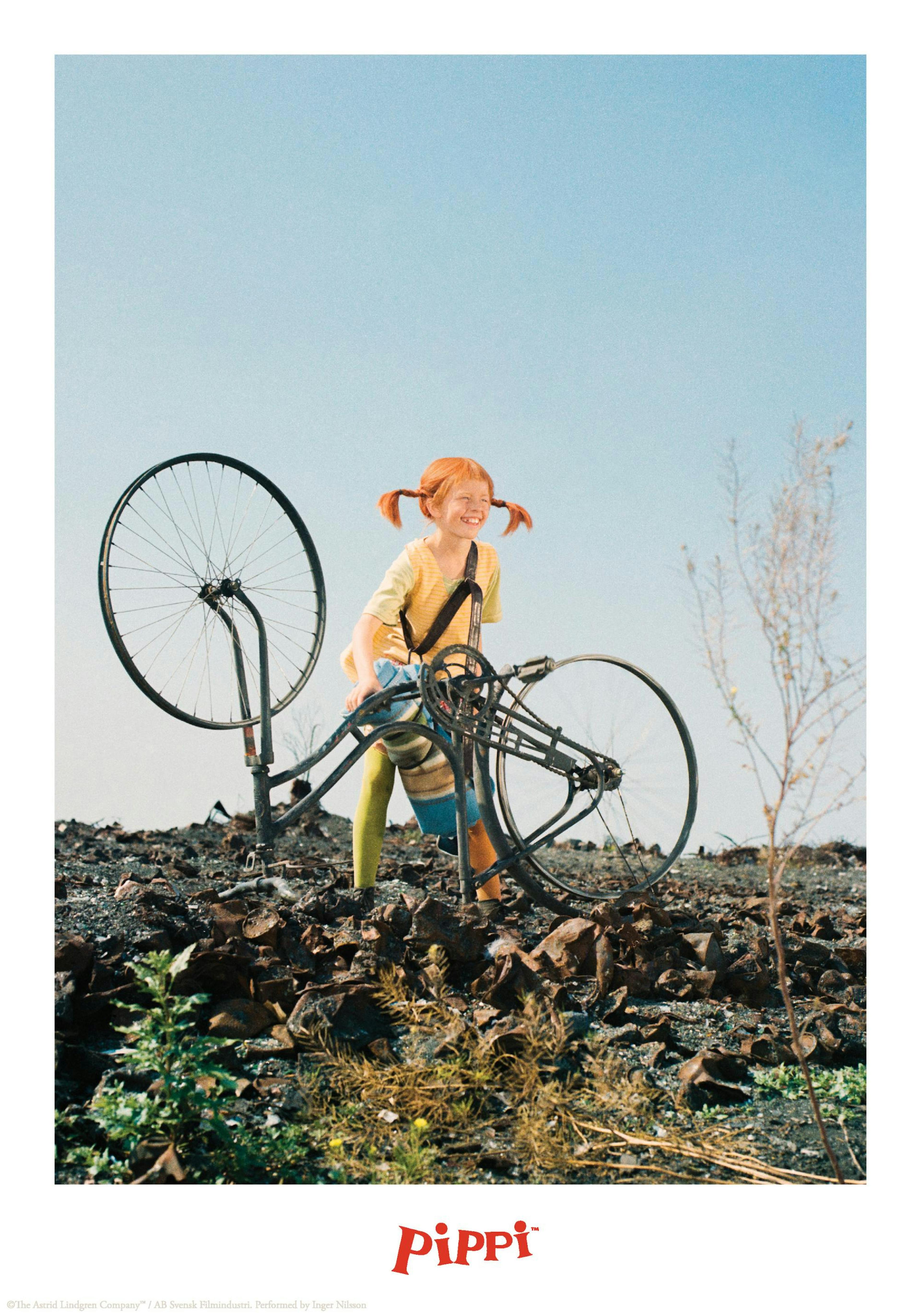 ピッピが自転車を持ち上げ、荒れた地面の上で笑っているポスター。