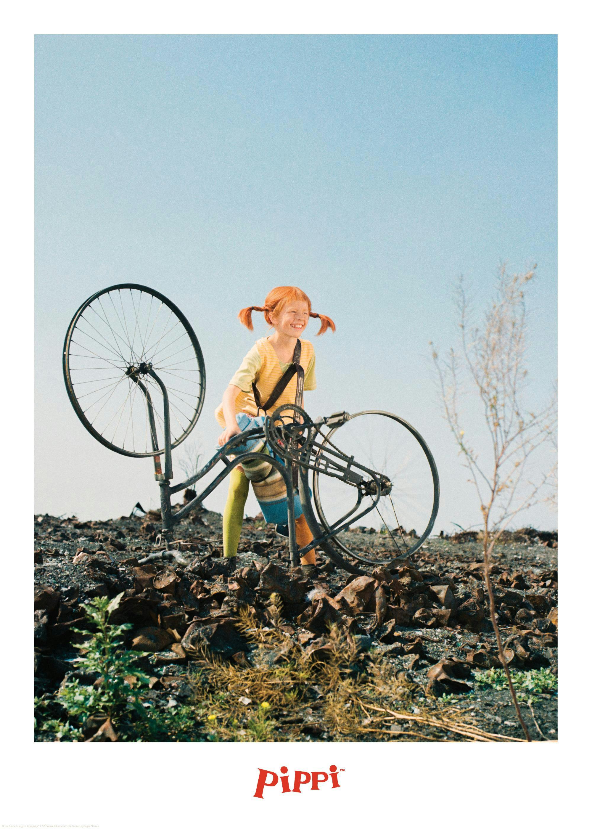 En Pippi plakat forestiller Pippi Langstrømpe med cyklen på en grå, ujævn mark med blå himmel.
