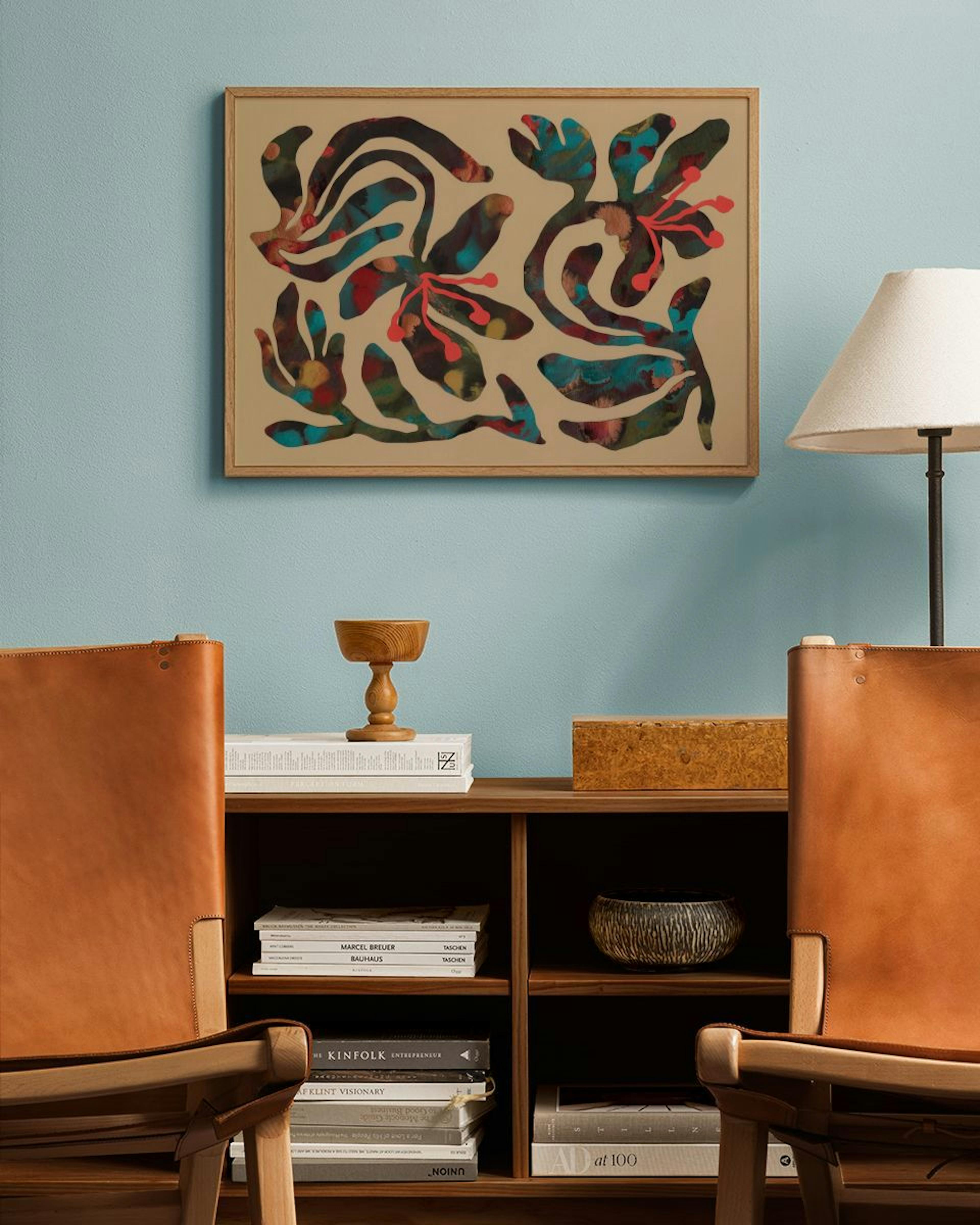 Abstract floral print with organic shapes in teal, red, and brown, displayed above a wooden shelf in a living room.