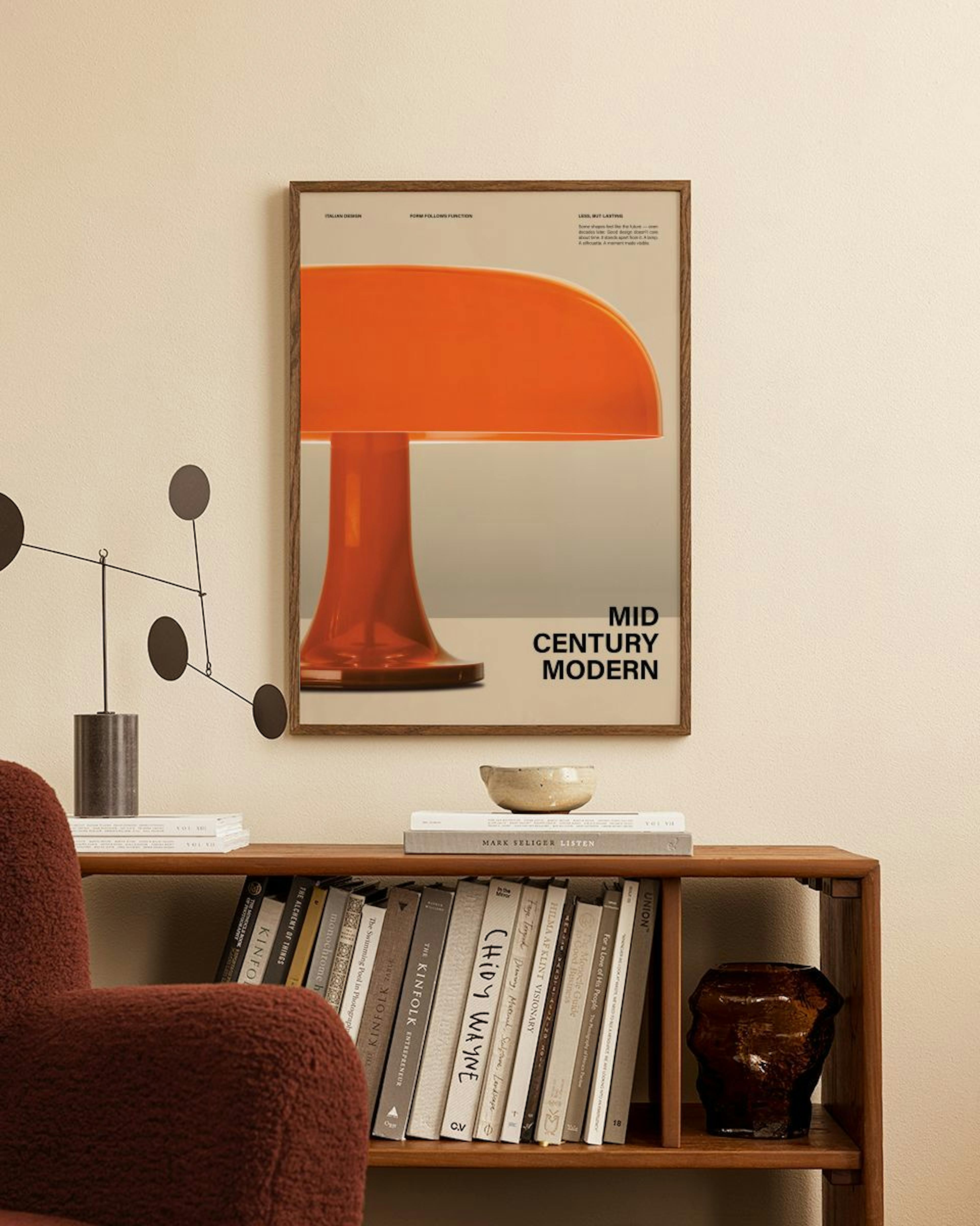 A Mid Century Modern print of an orange mushroom lamp, displayed above a wooden bookshelf with books and decor.