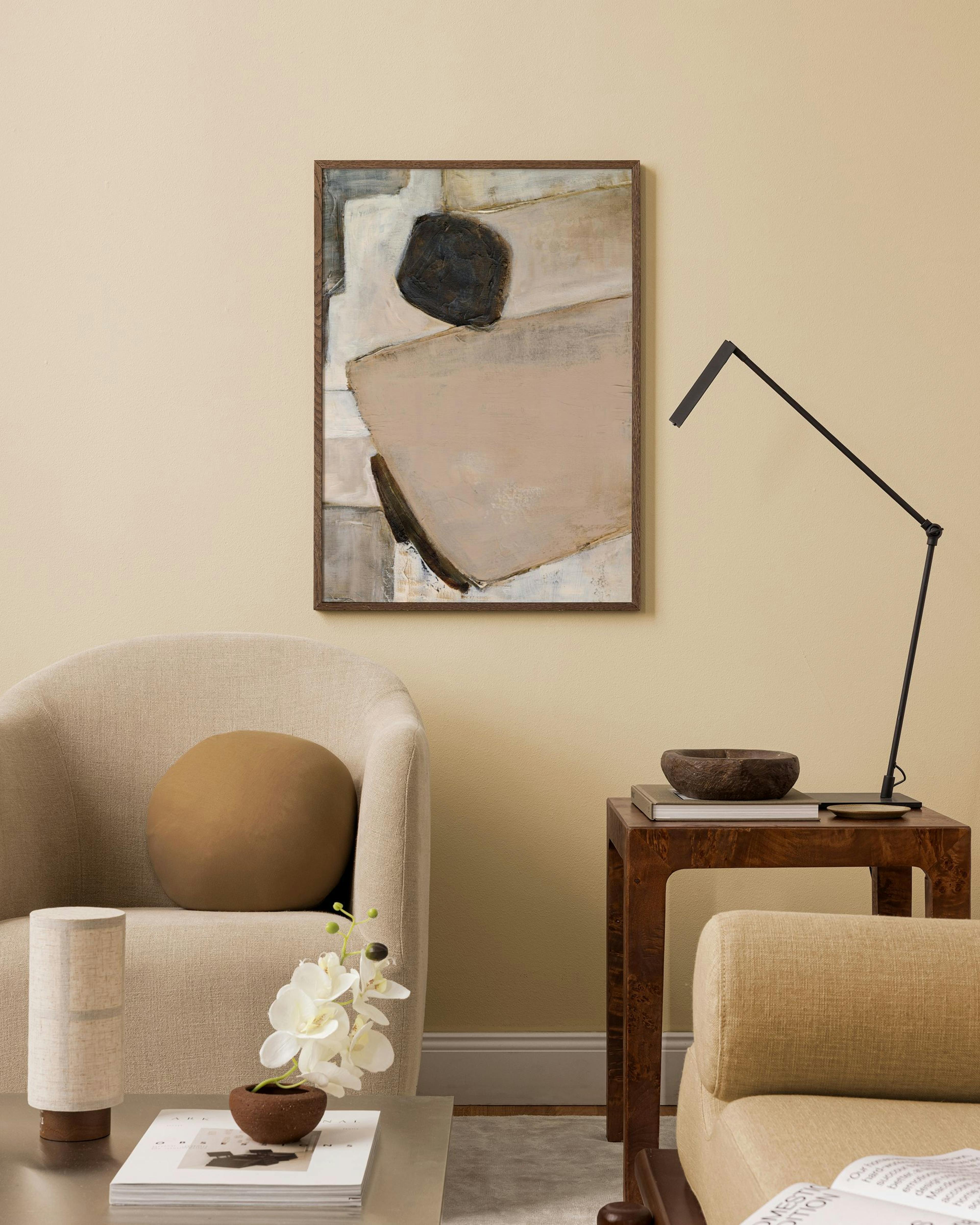 Abstract print with organic shapes in beige, white, and earthy tones hanging in a neutral modern living room.