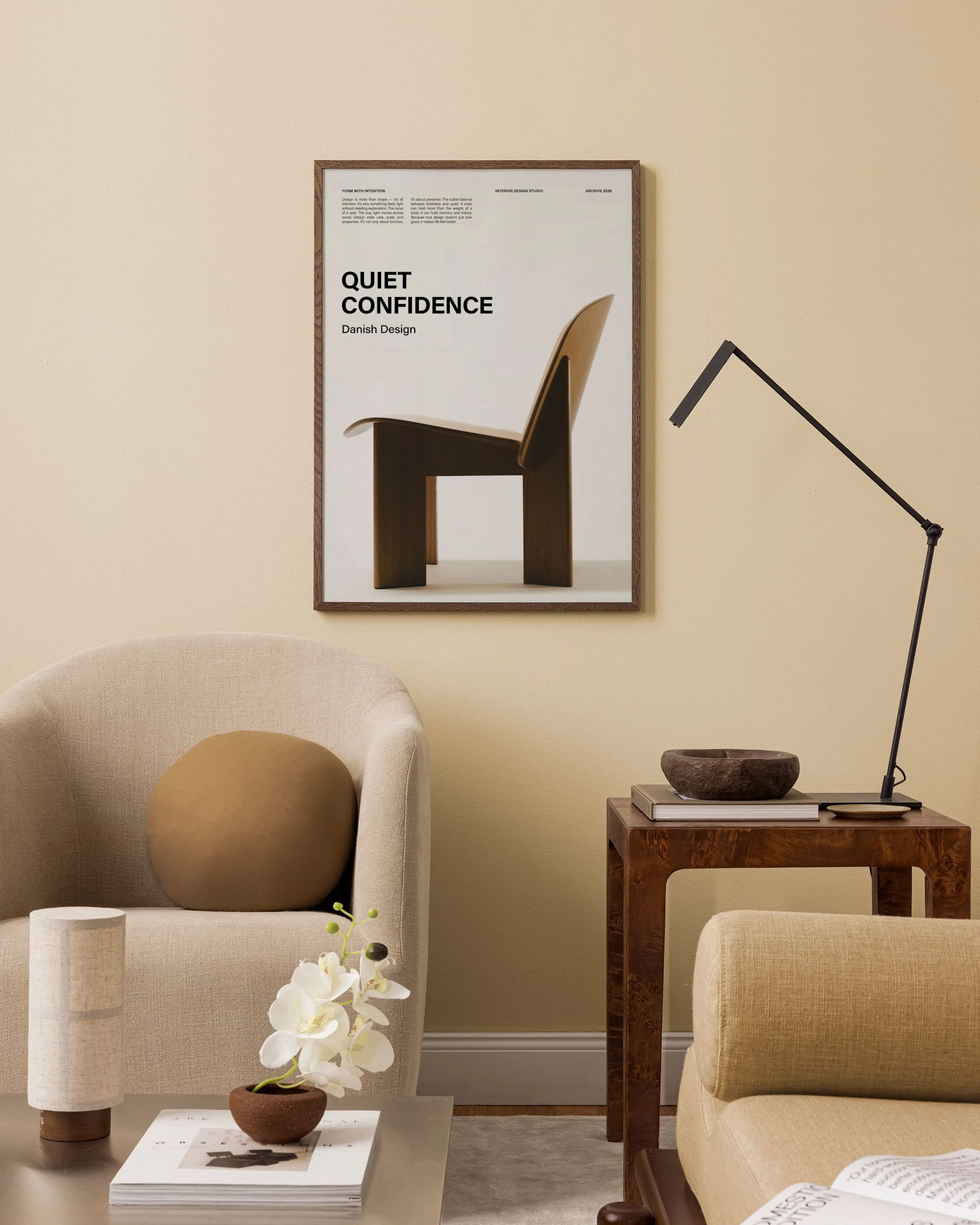 A print of a dark wood Danish design chair with Quiet Confidence text, hanging in a warm-toned living room above a beige armchai