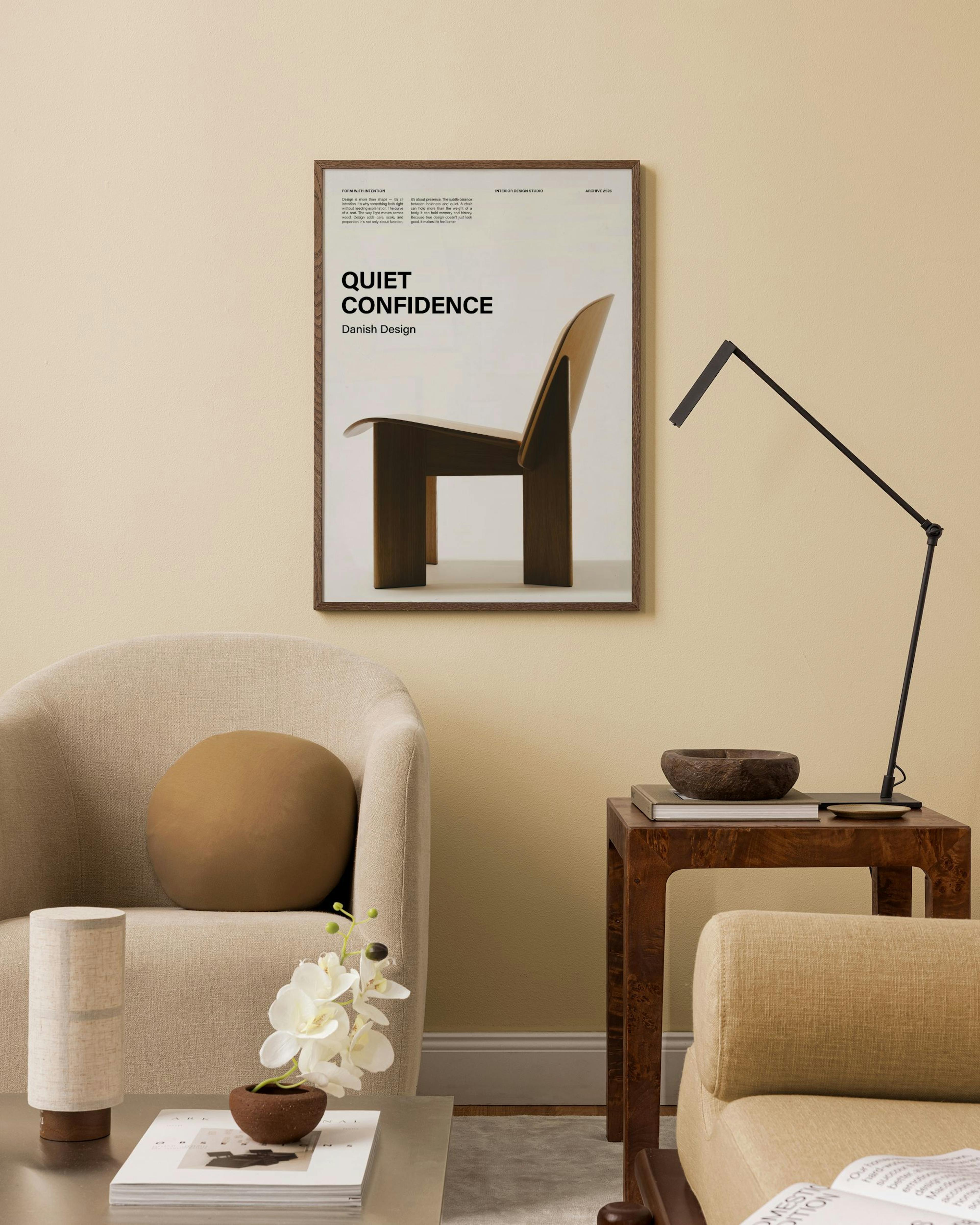 A print of a dark wood Danish design chair with Quiet Confidence text, hanging in a warm-toned living room above a beige armchai