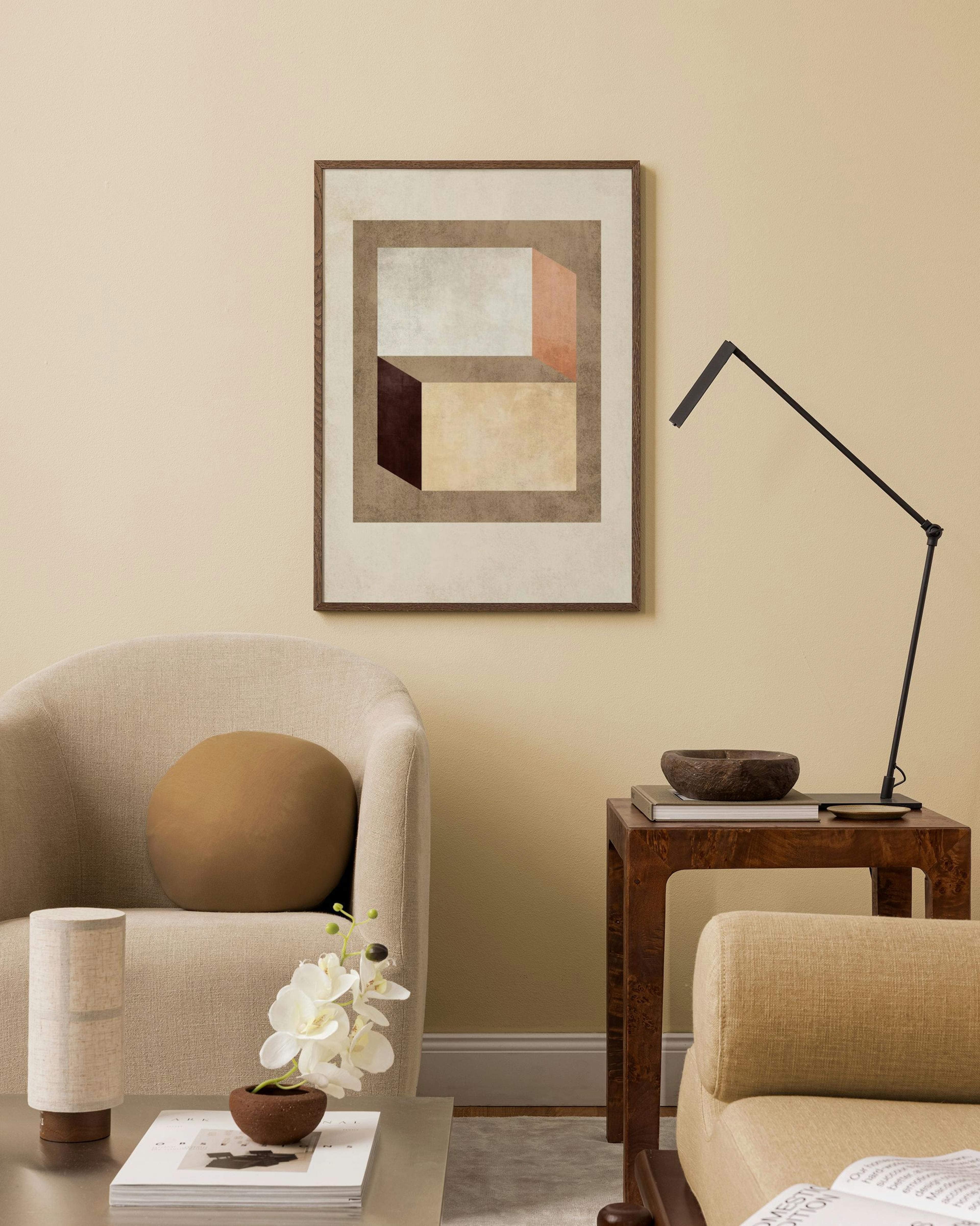 Póster de arte geométrico con formas rectangulares en tonos tierra, exhibido en una sala de estar moderna sobre un sillón.