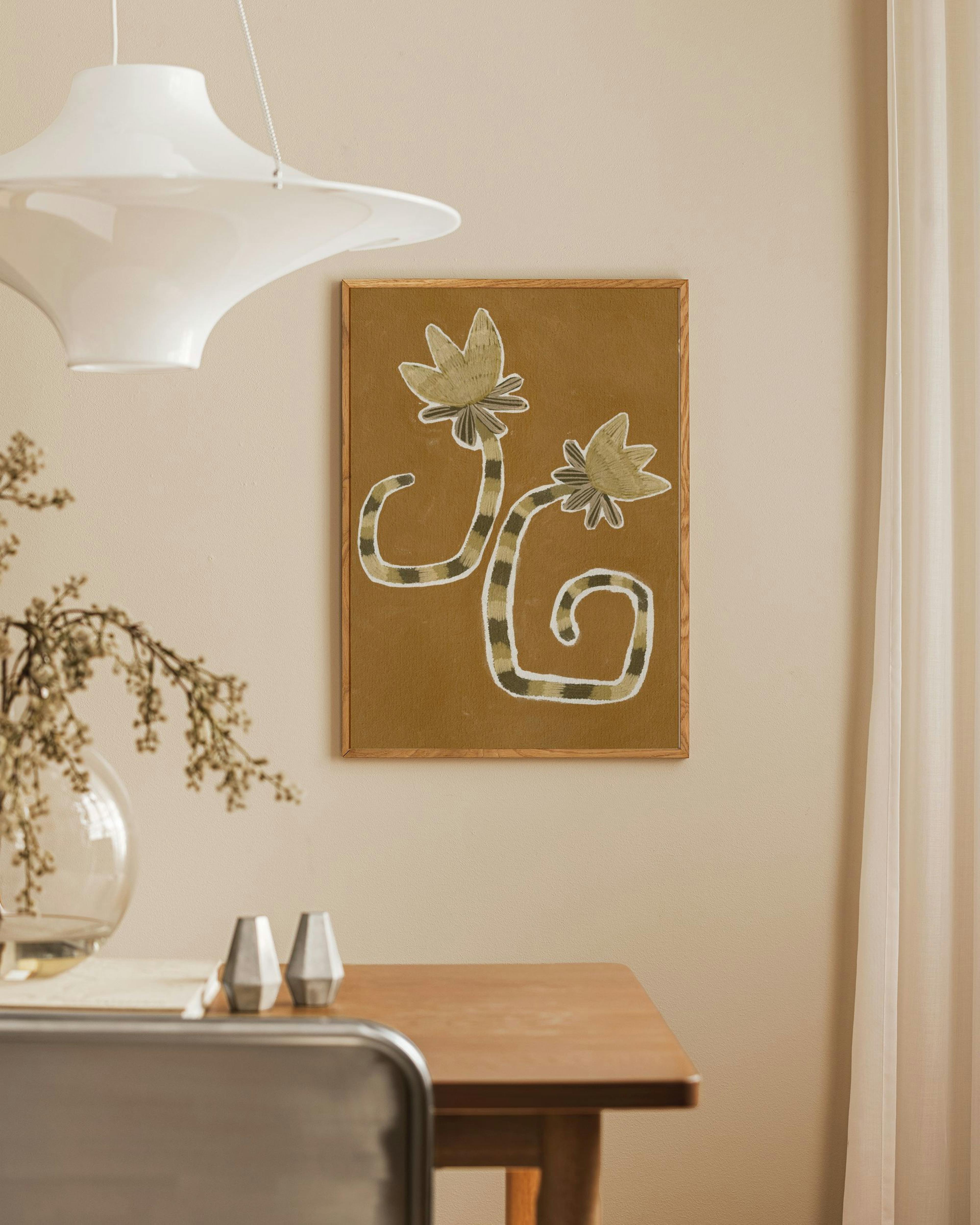 A print of two stylized brown and green flowers on a textured orange background, hanging above a wooden table in a dining room.