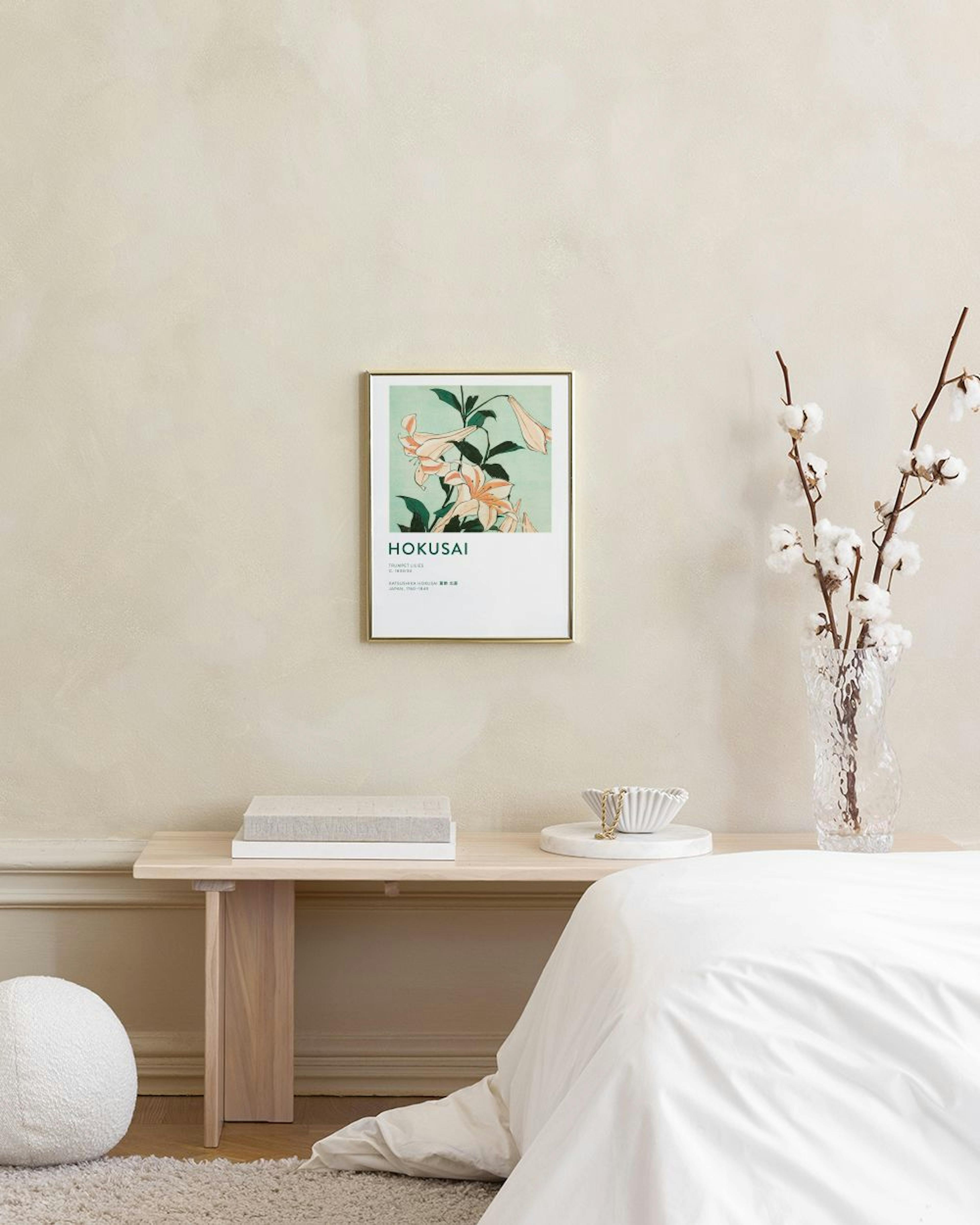 Affiche Hokusai avec des lys orange pâle sur fond vert clair, accrochée au mur dans un salon moderne.