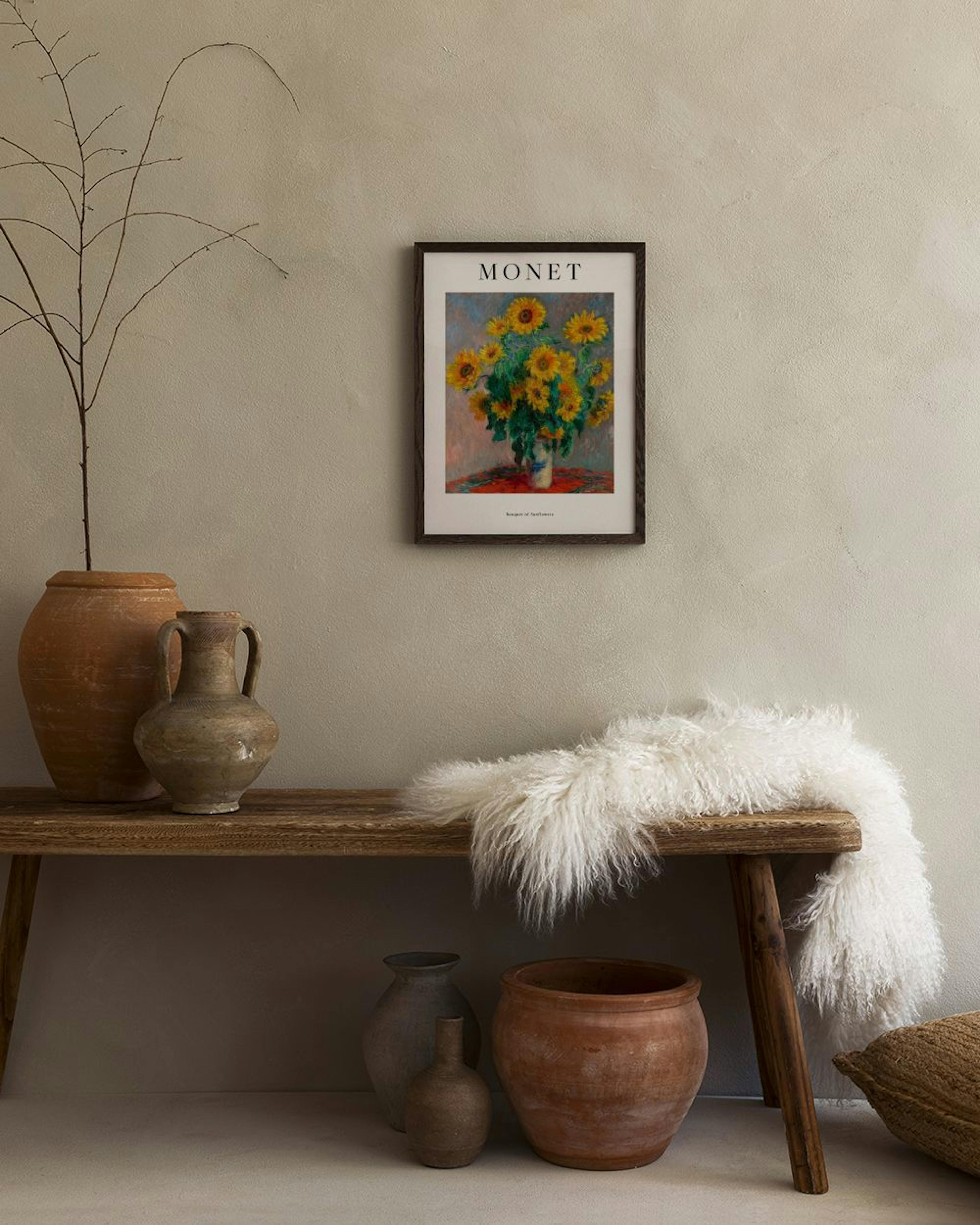 Poster di Monet con girasoli in un vaso, appeso a una parete chiara sopra una poltrona scura in un ambiente moderno.