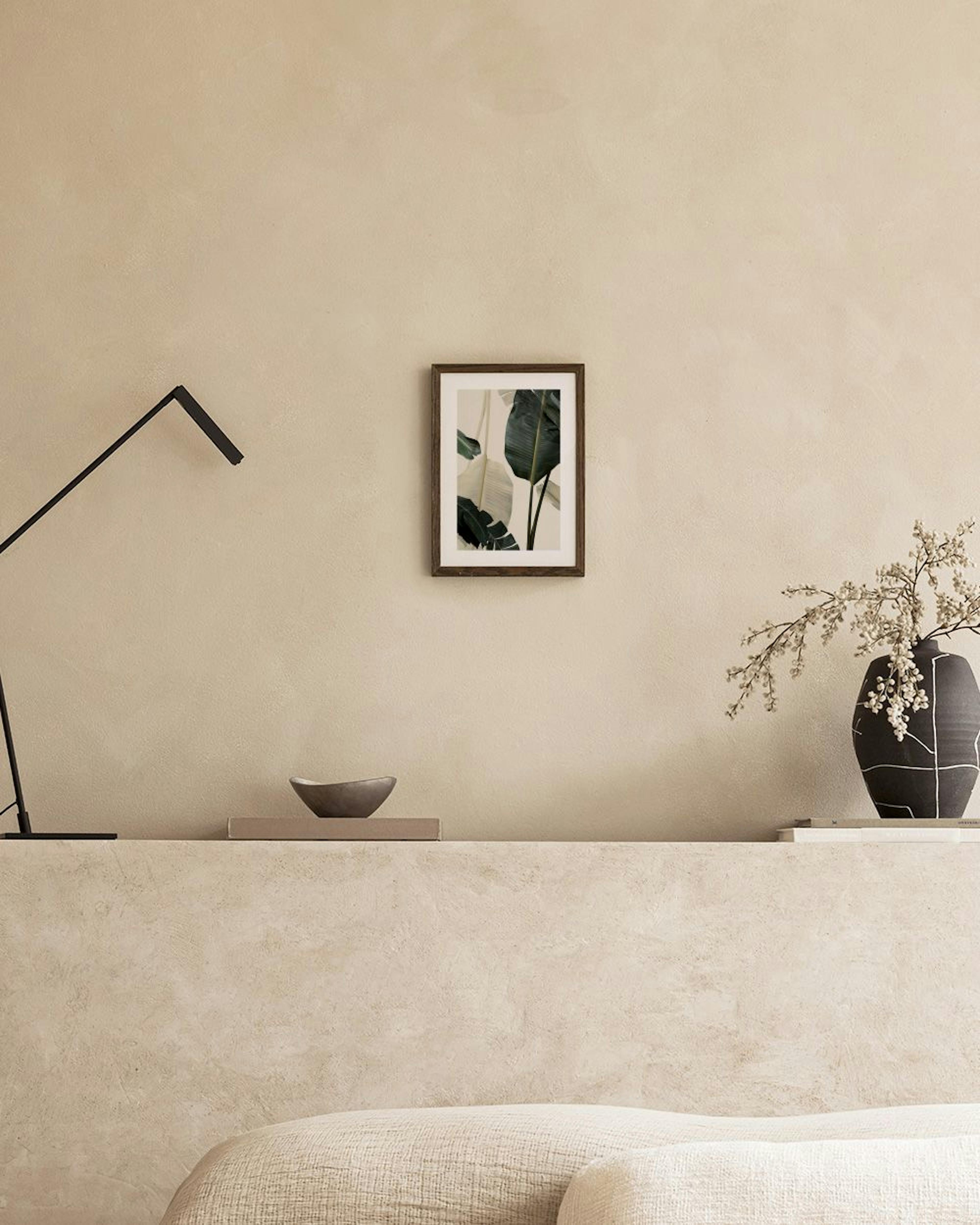 Poster con foglie di palma verdi scure e chiare, appeso sopra un mobile bianco con un vaso e una sedia.