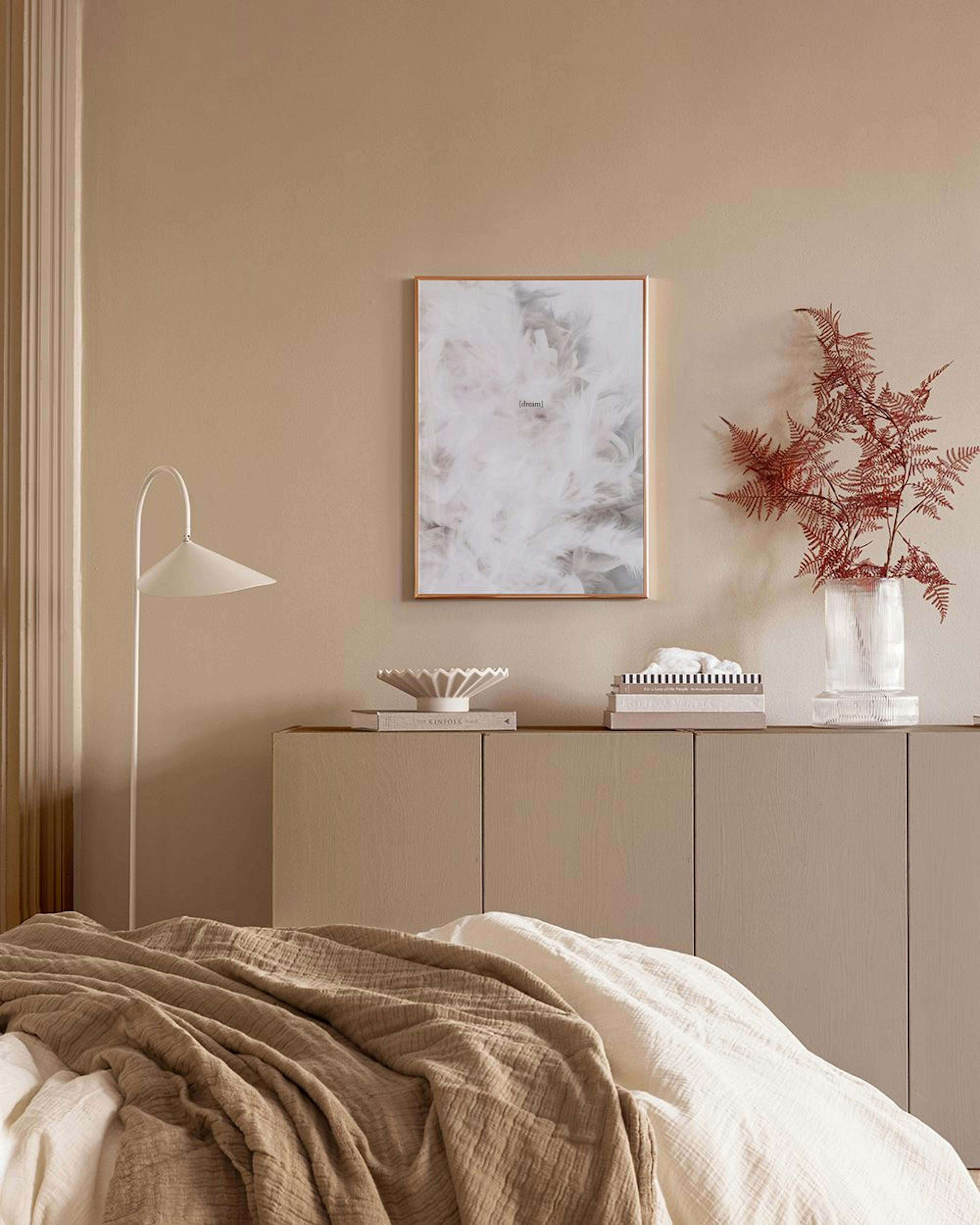 Affiche de plumes blanches douces avec le texte dream, accrochée sur une grille murale noire, à côté dune chaise en bois avec un