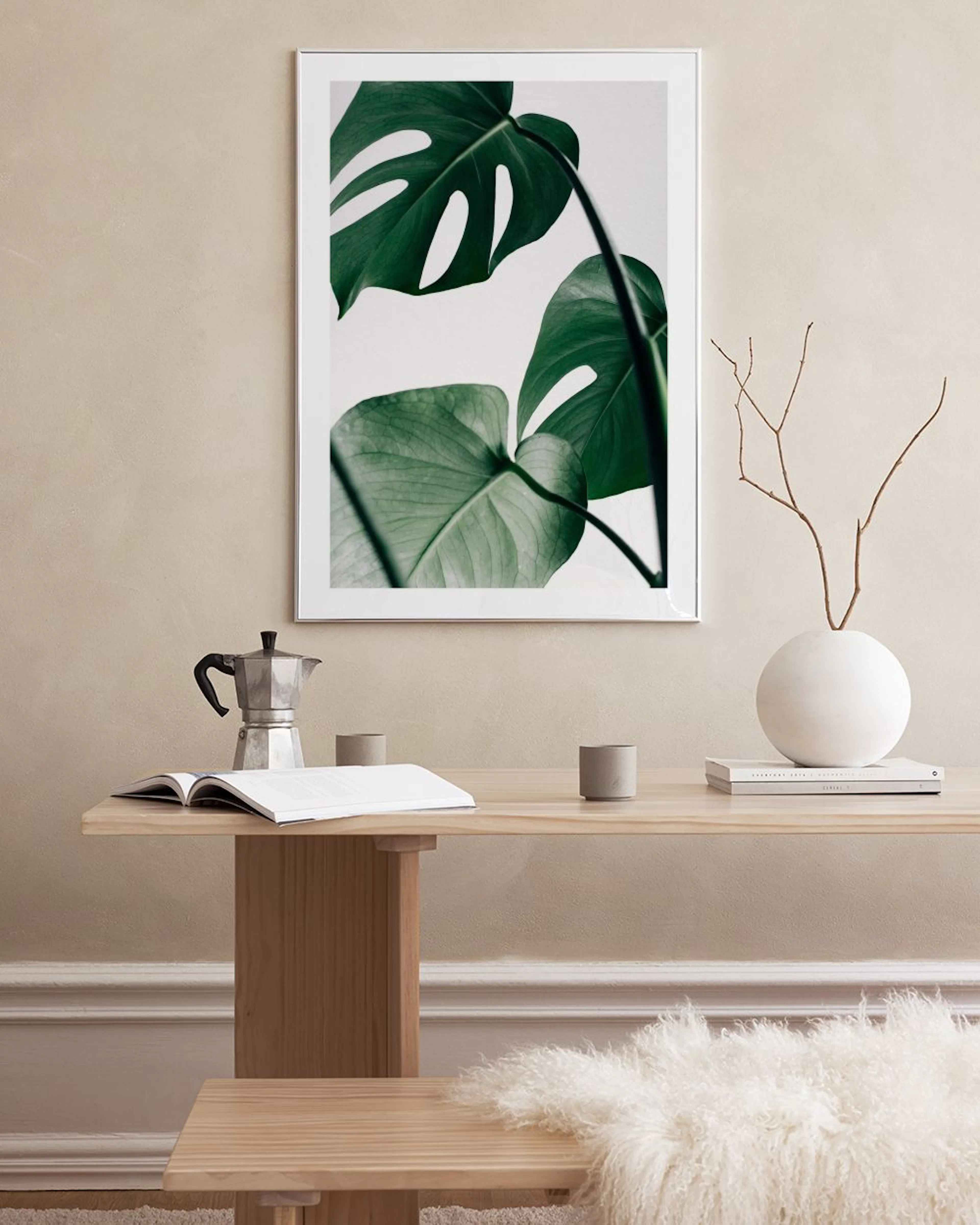 Affiche avec feuilles de Monstera vertes sur fond blanc, accrochée à une grille murale dans un bureau moderne.