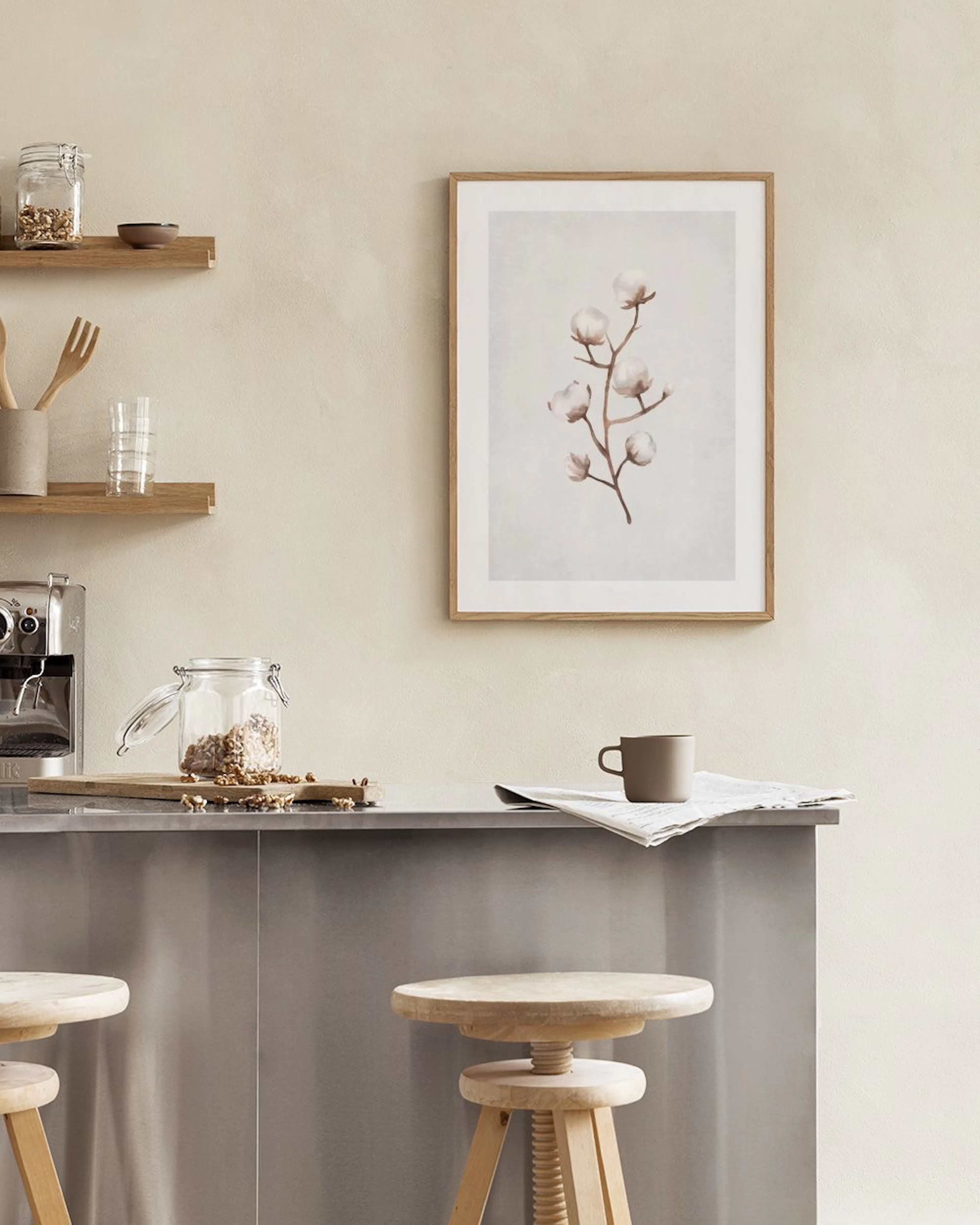 A minimalist print of a cotton branch with fluffy white blossoms, displayed above a white console table with neutral vases and b