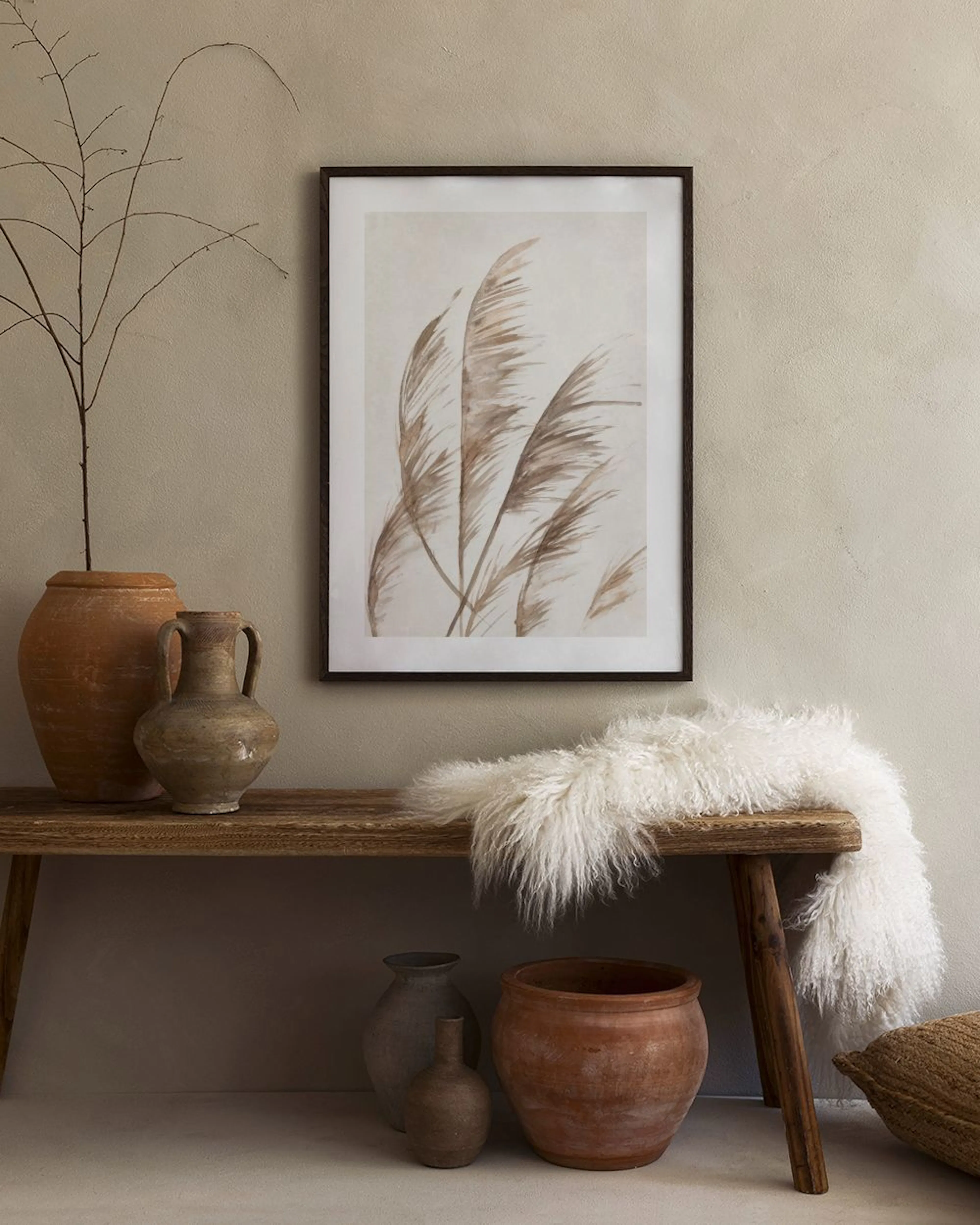 Póster de hierbas de pampa en tonos tierra, exhibido sobre una mesa con jarrones blancos en una sala moderna.