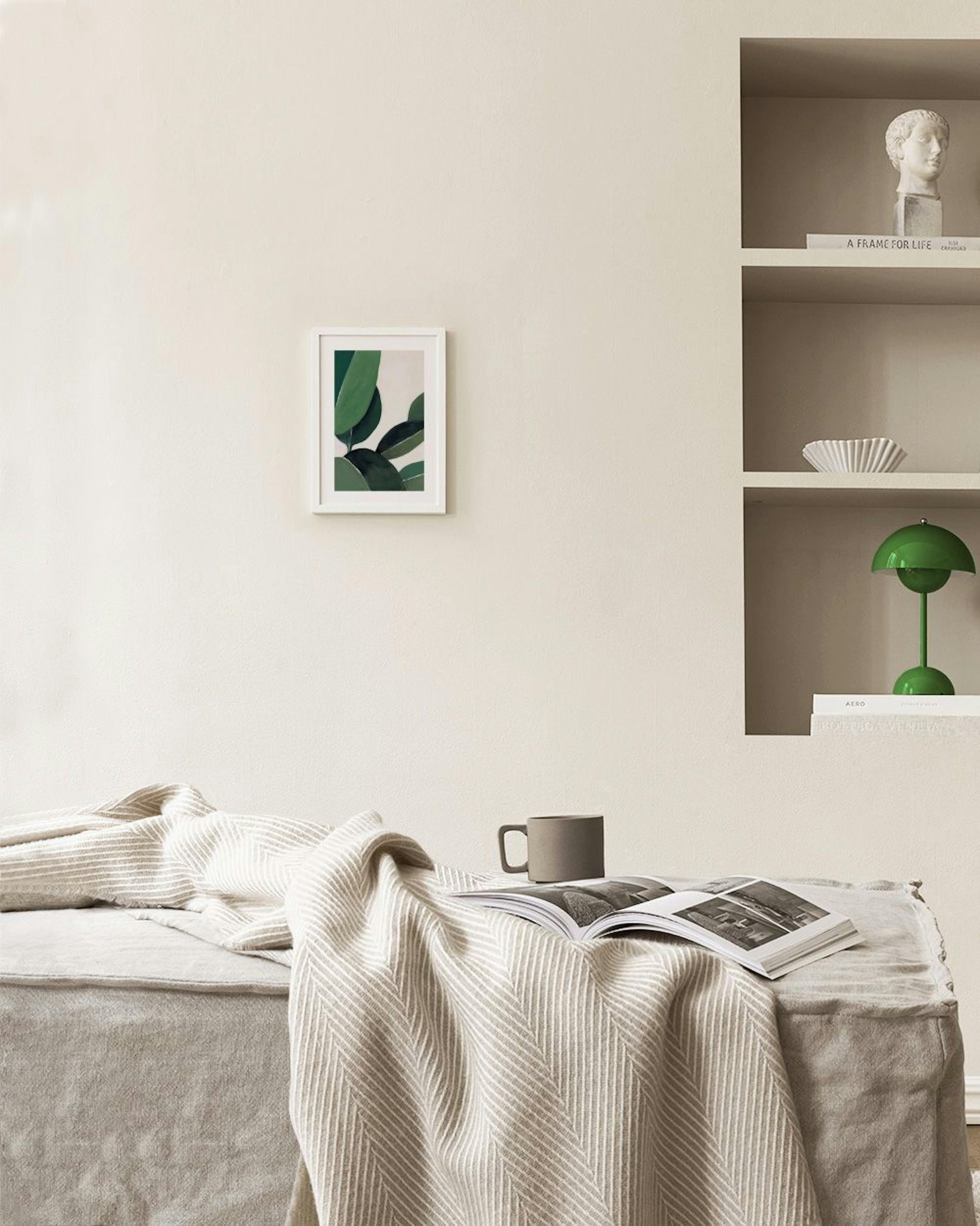 Poster mit grünen Blättern in verschiedenen Grüntönen, hängend über einem grünen Sideboard mit Büchern und Deko.