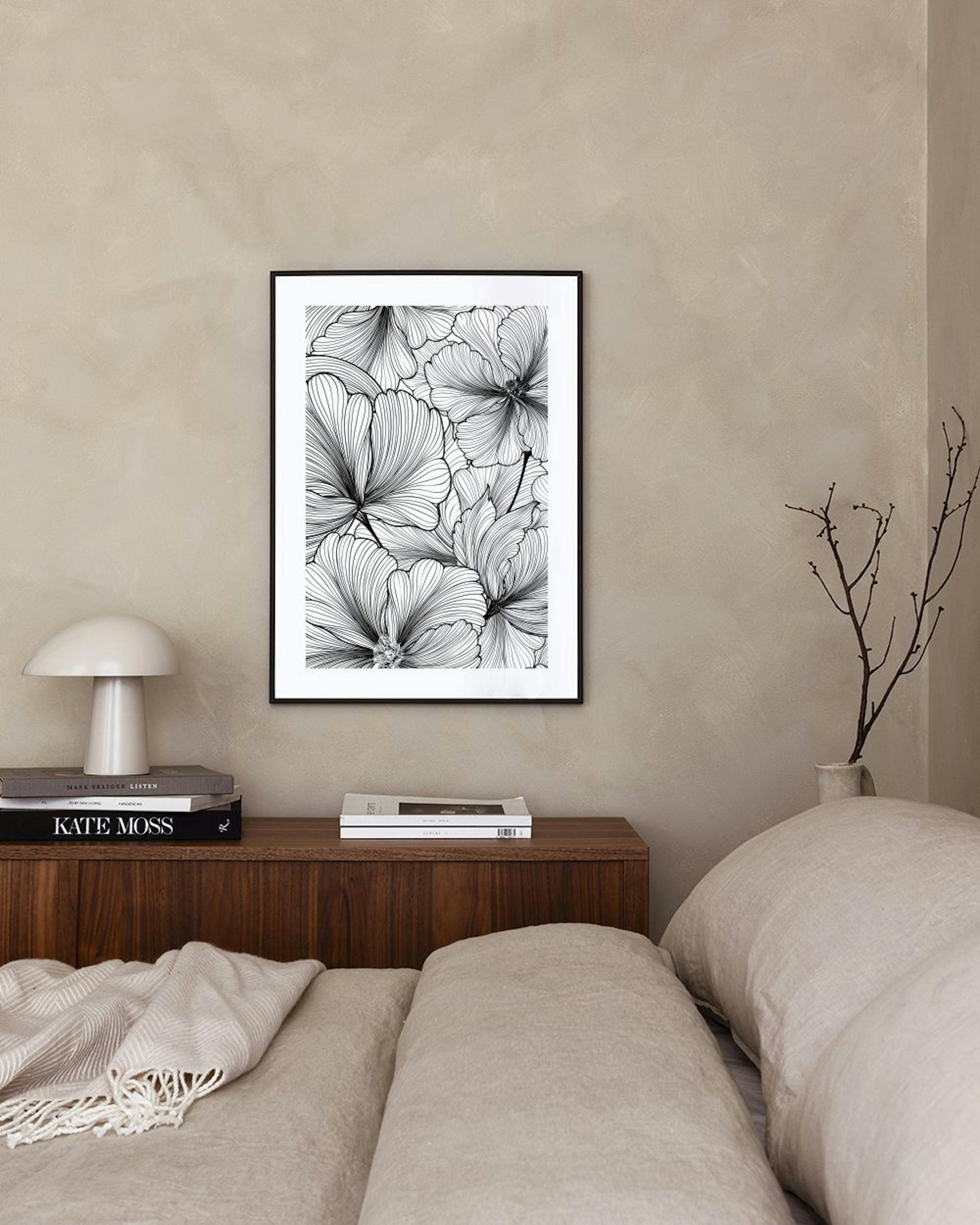 Poster met illustratie van zwarte lijntekeningen van bloemen, hangend boven een zwarte tafel met boeken en een plant.