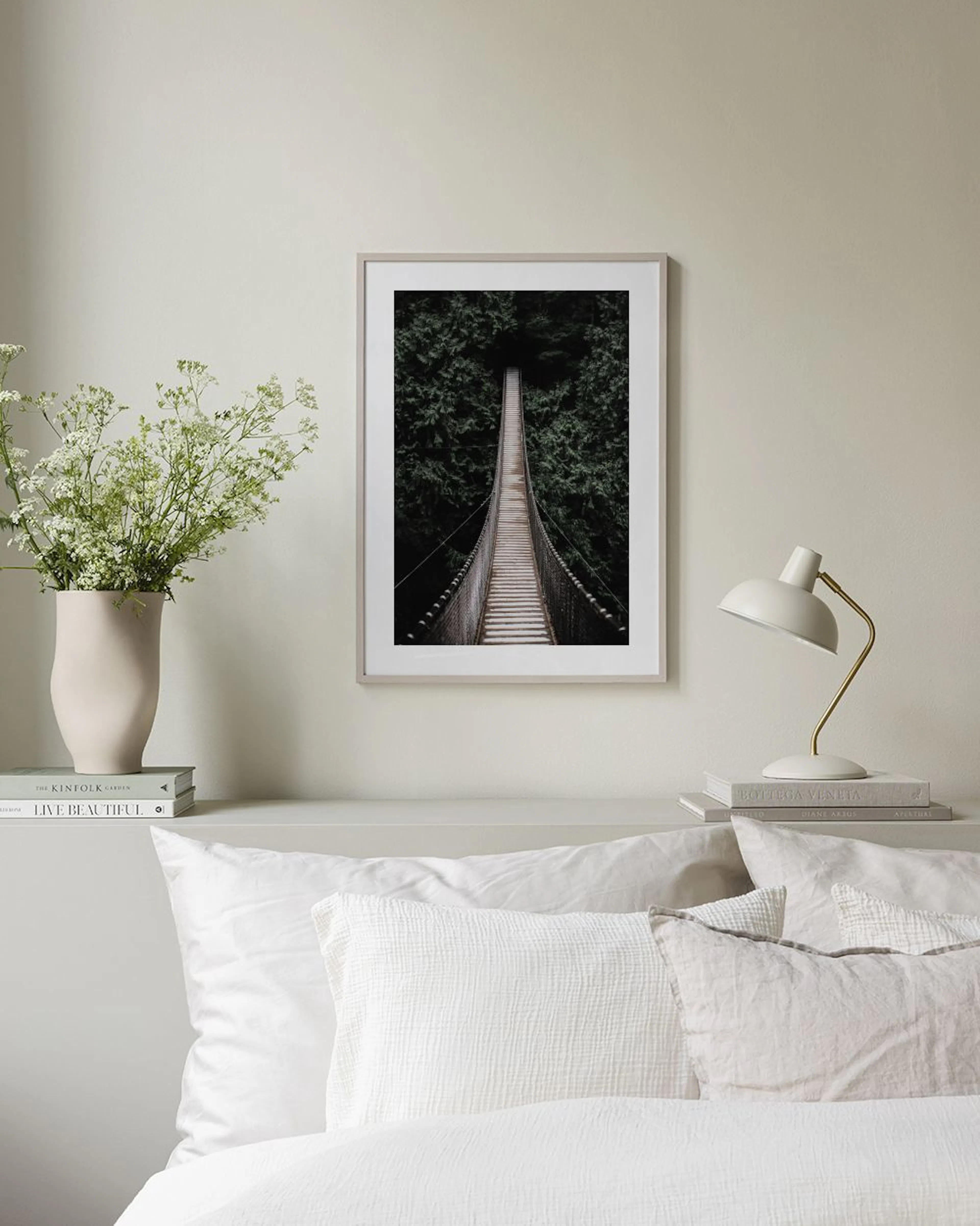 Affiche dun pont suspendu en bois dans une forêt sombre, affichée au-dessus dun meuble blanc dans un salon.