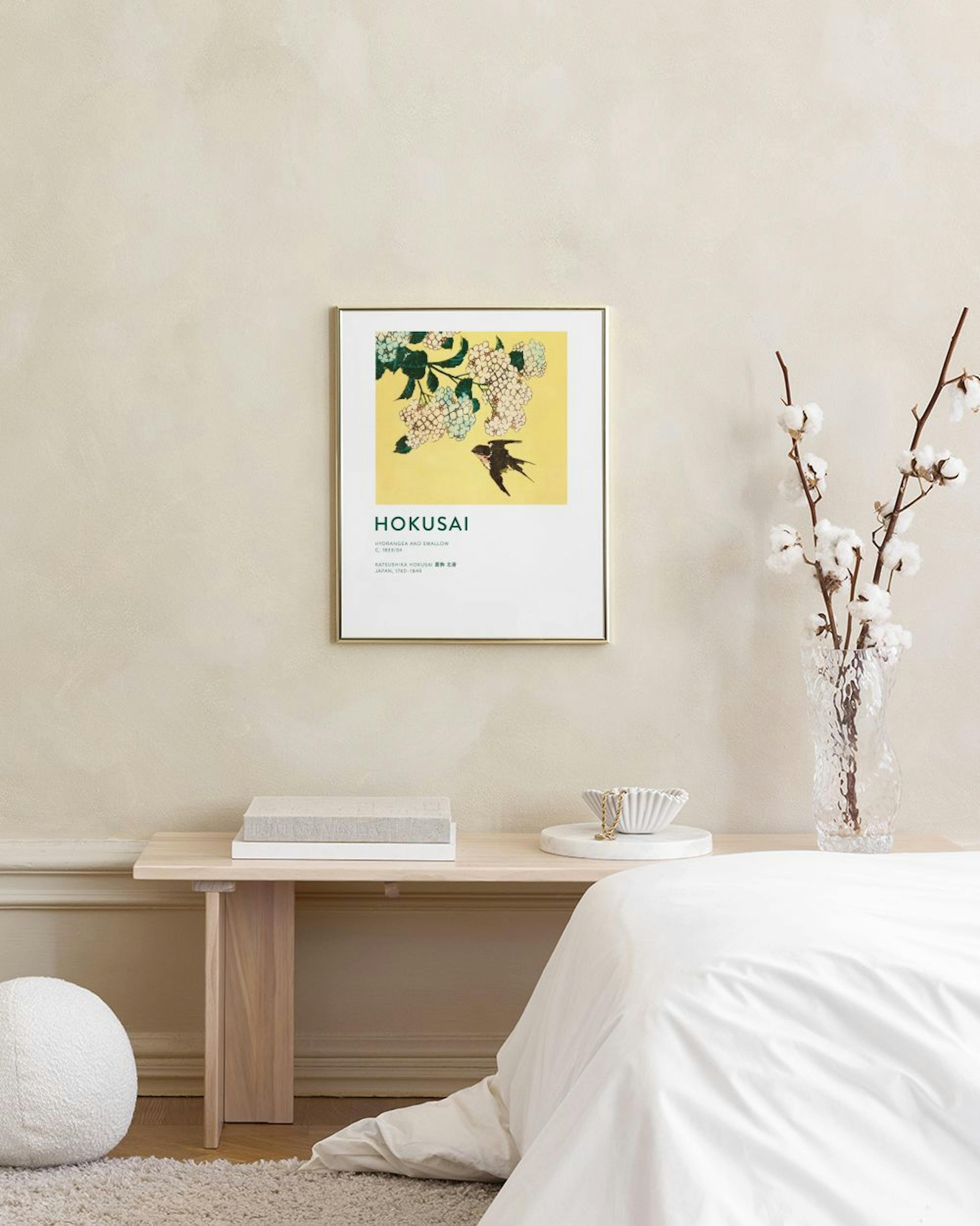 Affiche Hokusai dune hirondelle sous des fleurs blanches et vertes sur un fond jaune, au-dessus dune commode blanche avec un vas