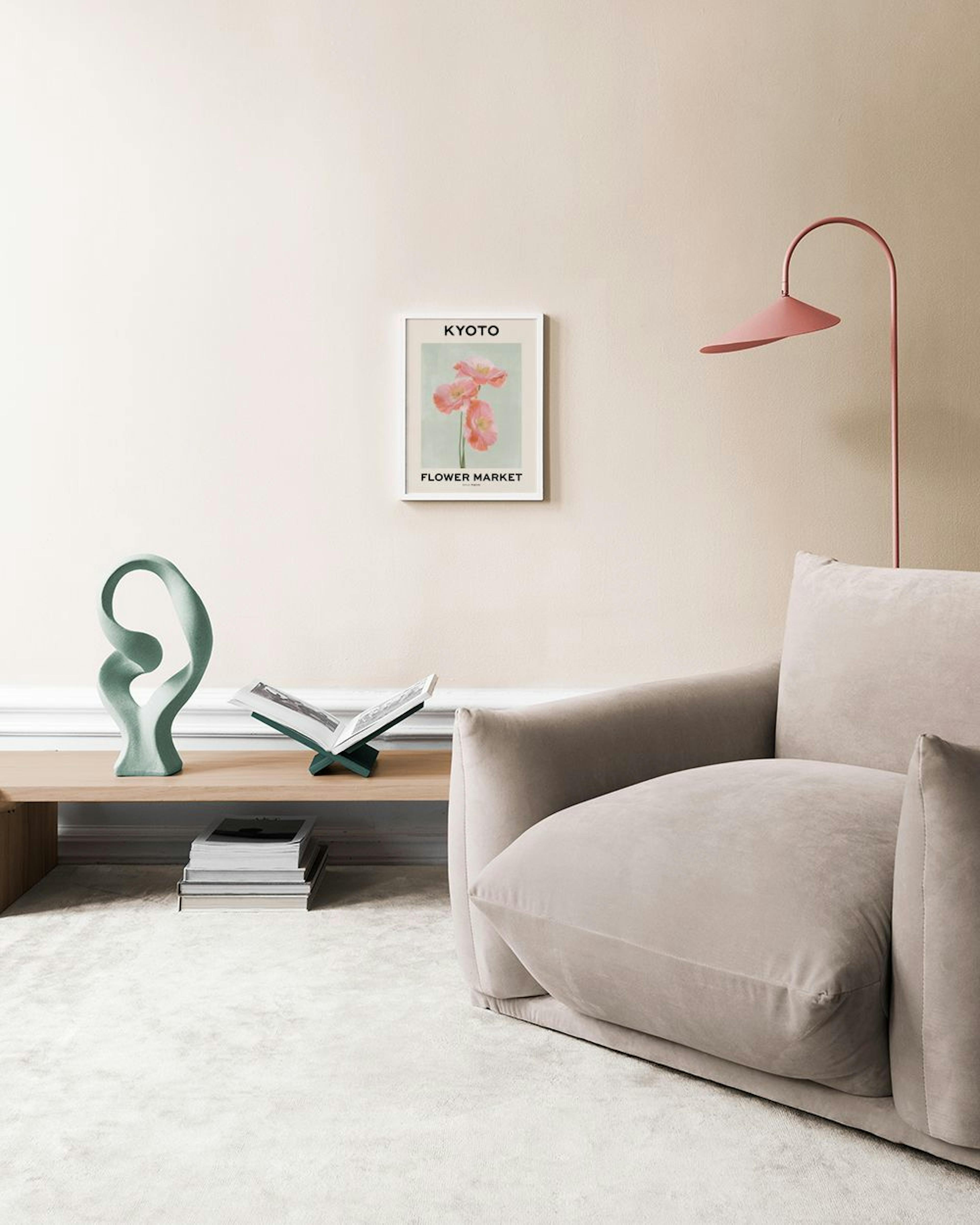Affiche Kyoto Flower Market avec trois coquelicots roses sur fond vert clair, accrochée au mur au-dessus dun tabouret.