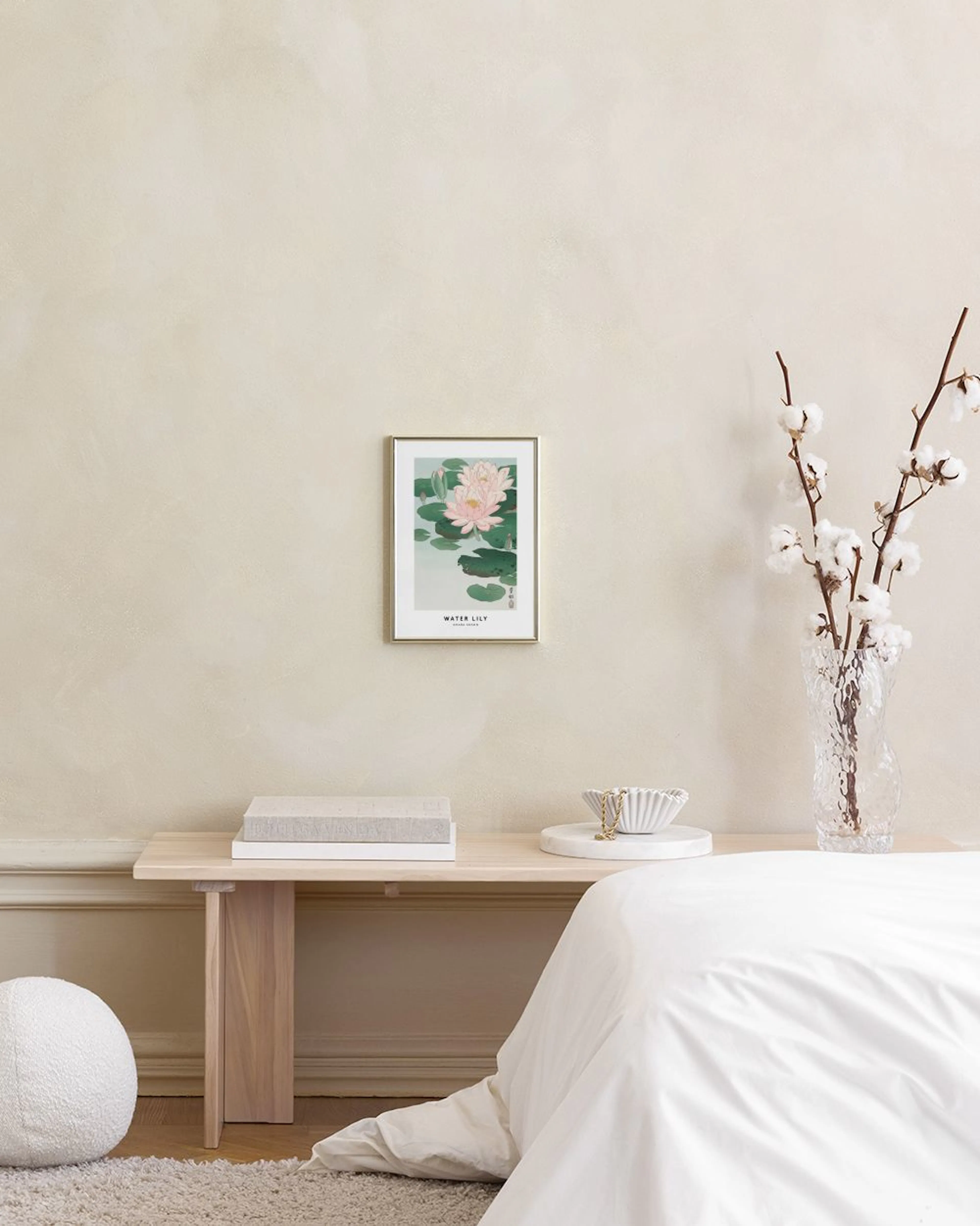 Affiche avec des nénuphars roses sur leau, posée sur une étagère en béton avec des objets décoratifs et une lampe.