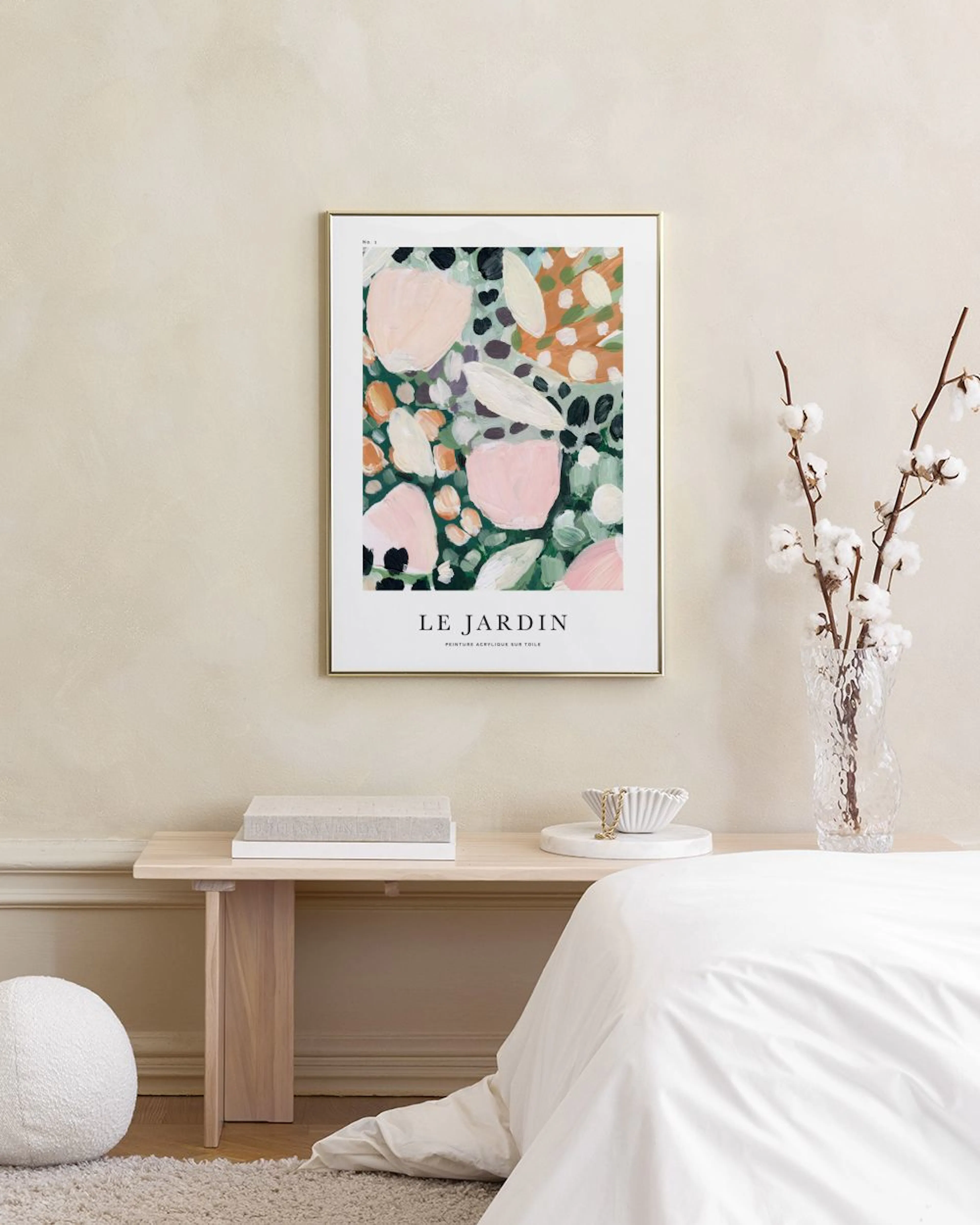 Poster med organiska former i rosa, grönt och orange, med texten LE JARDIN, hängande ovanför en mörk soffa.