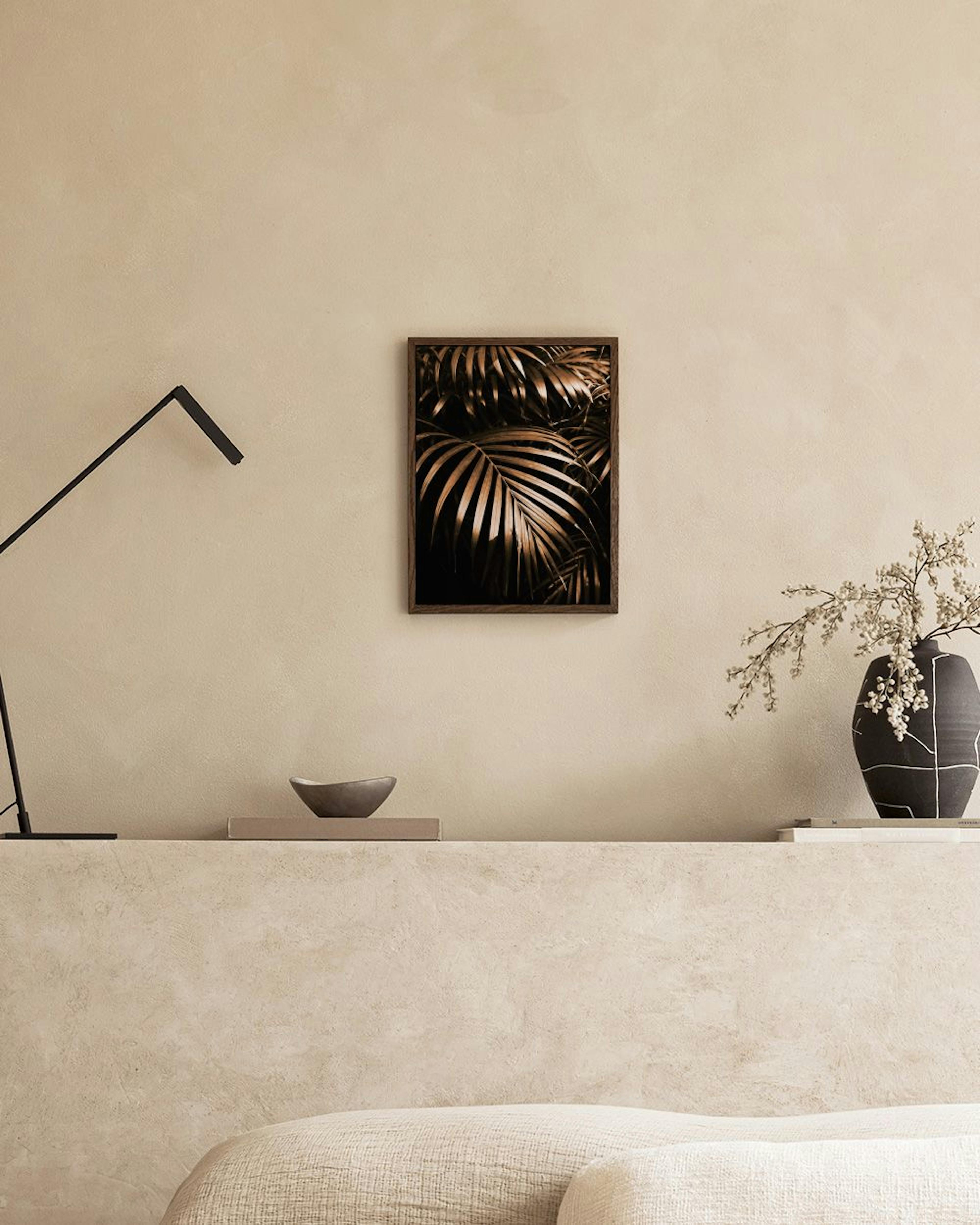 Poster mit goldenen Palmenblättern auf schwarzem Hintergrund, über einem Sideboard mit Büchern und Dekoration.