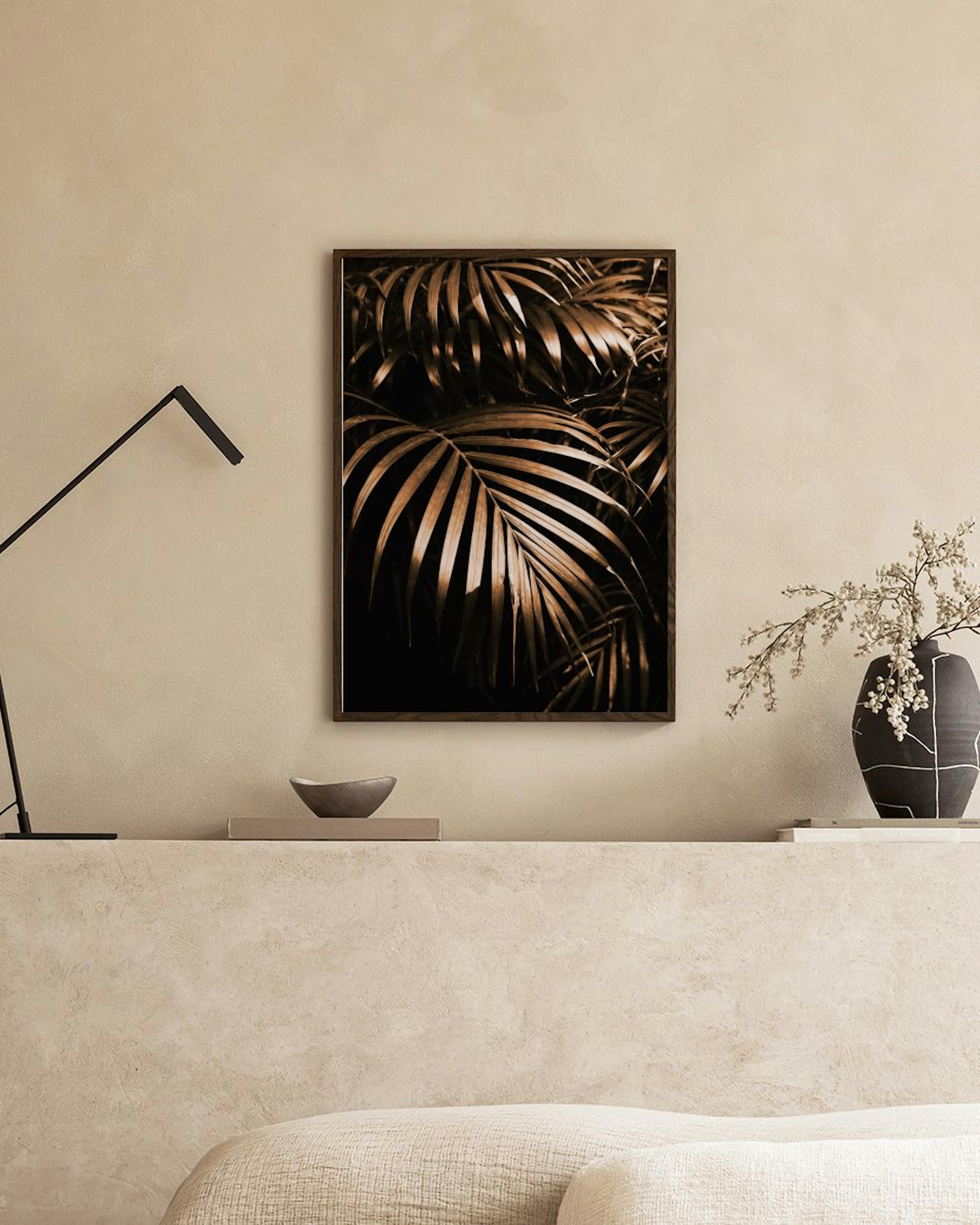 Póster de hojas de palmera doradas sobre fondo oscuro, colgado sobre un mueble con libros y decoración.