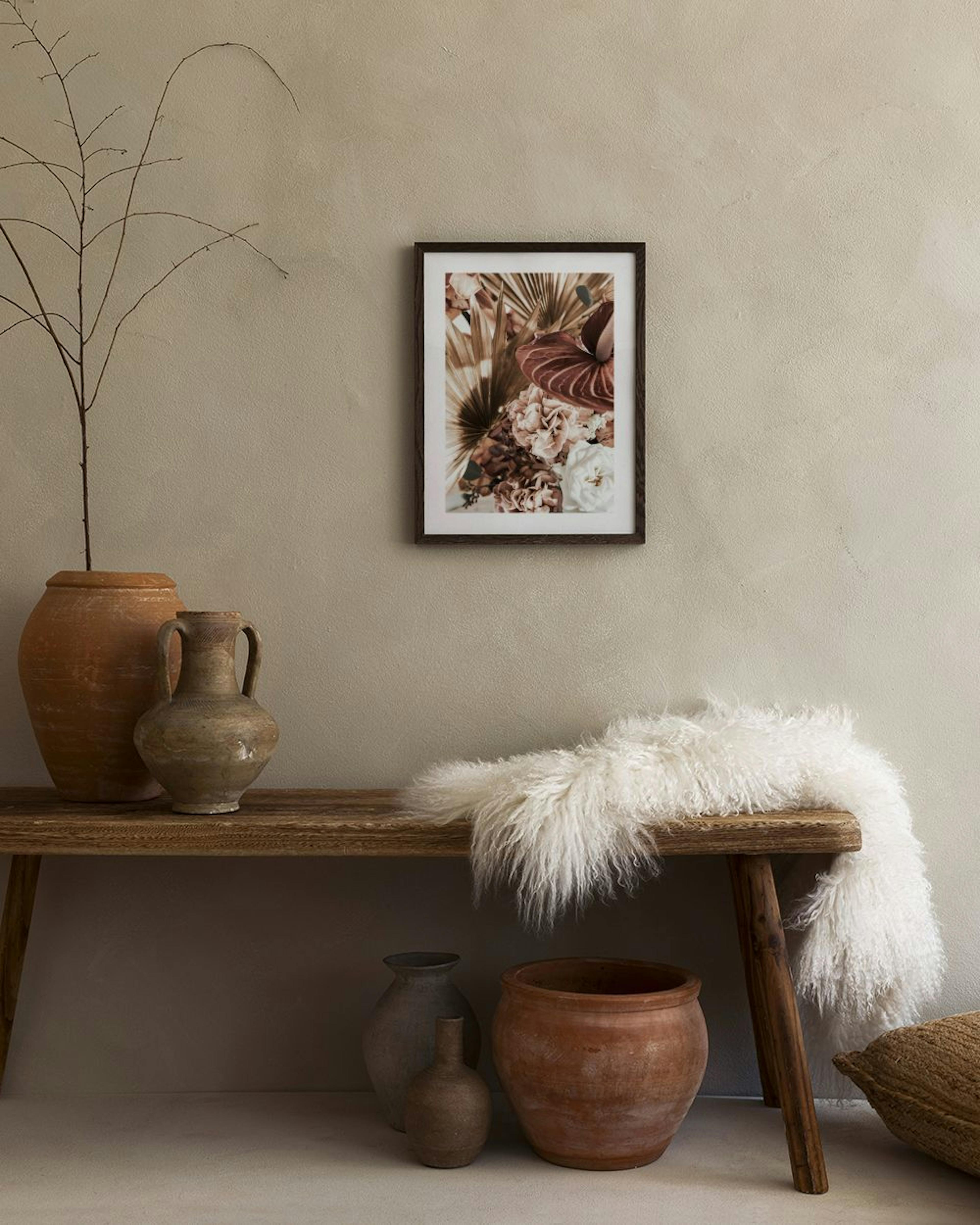 Poster con fiori e foglie tropicali dai toni caldi, appeso in un soggiorno moderno accanto a una poltrona e un tavolino.
