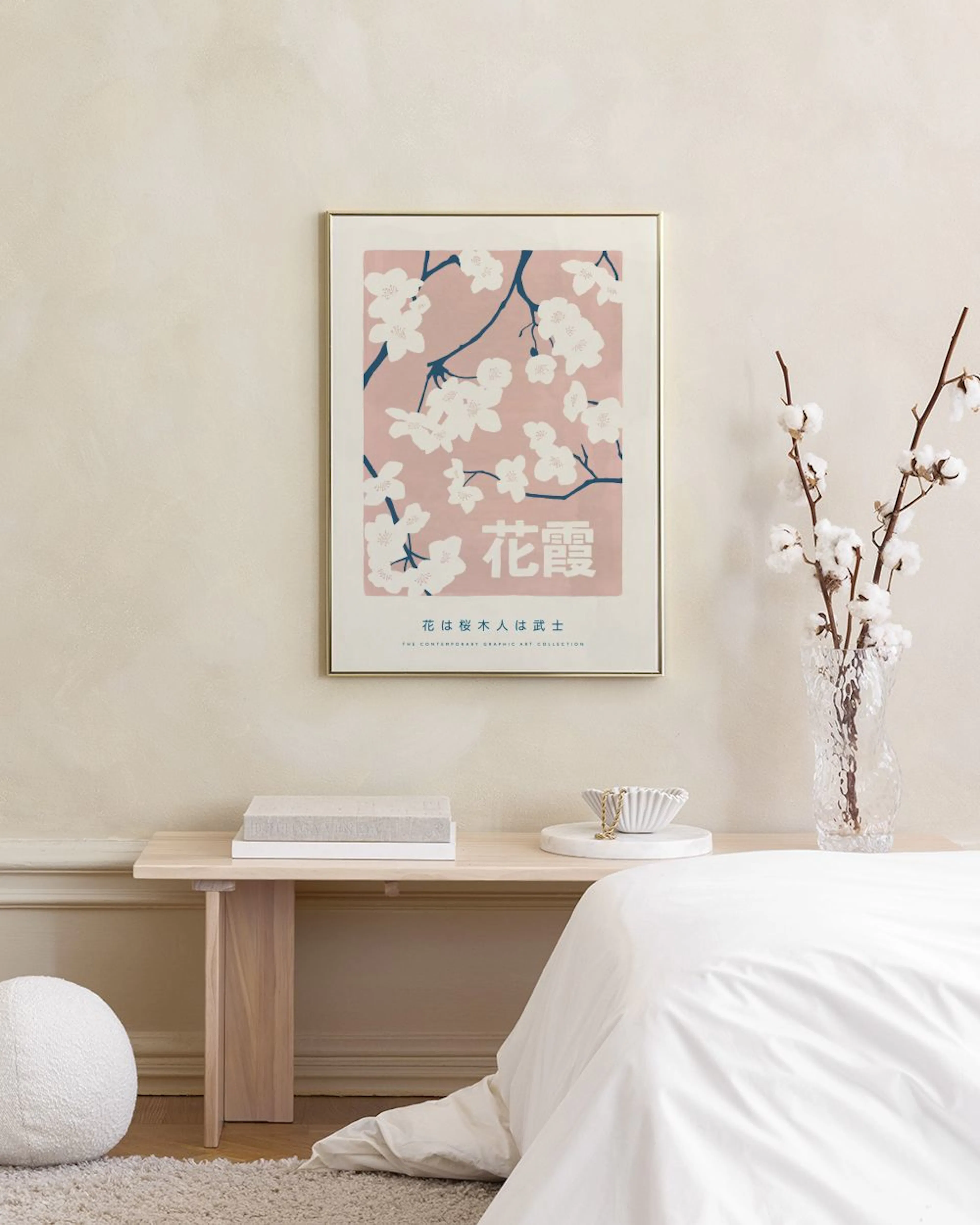 A poster featuring a Japanese cherry blossom design with white flowers and dark branches on a pink background, hanging above a w