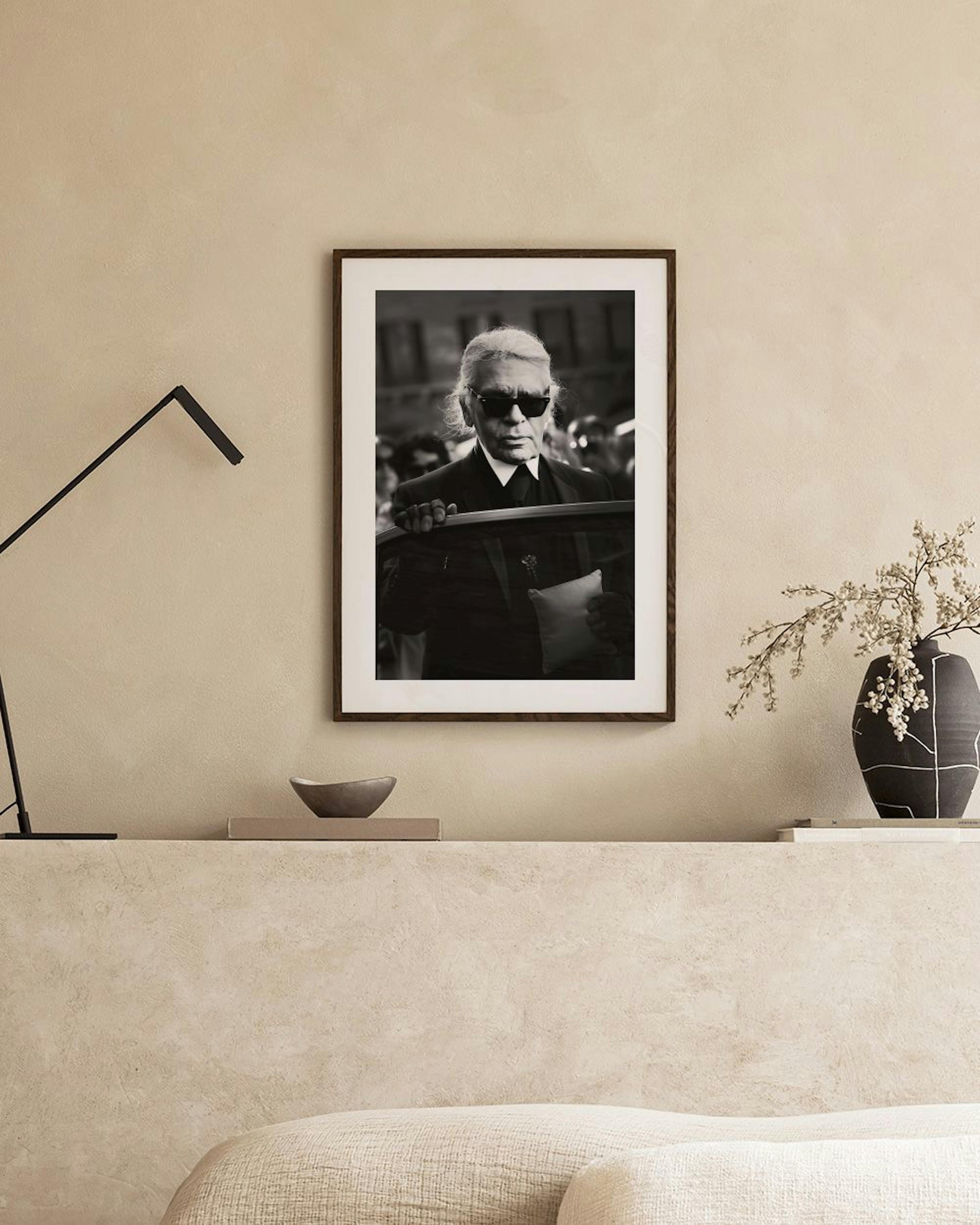 Zwart-wit poster van Karl Lagerfeld met zonnebril, hangend boven een wit dressoir met vaas en pampasgras.