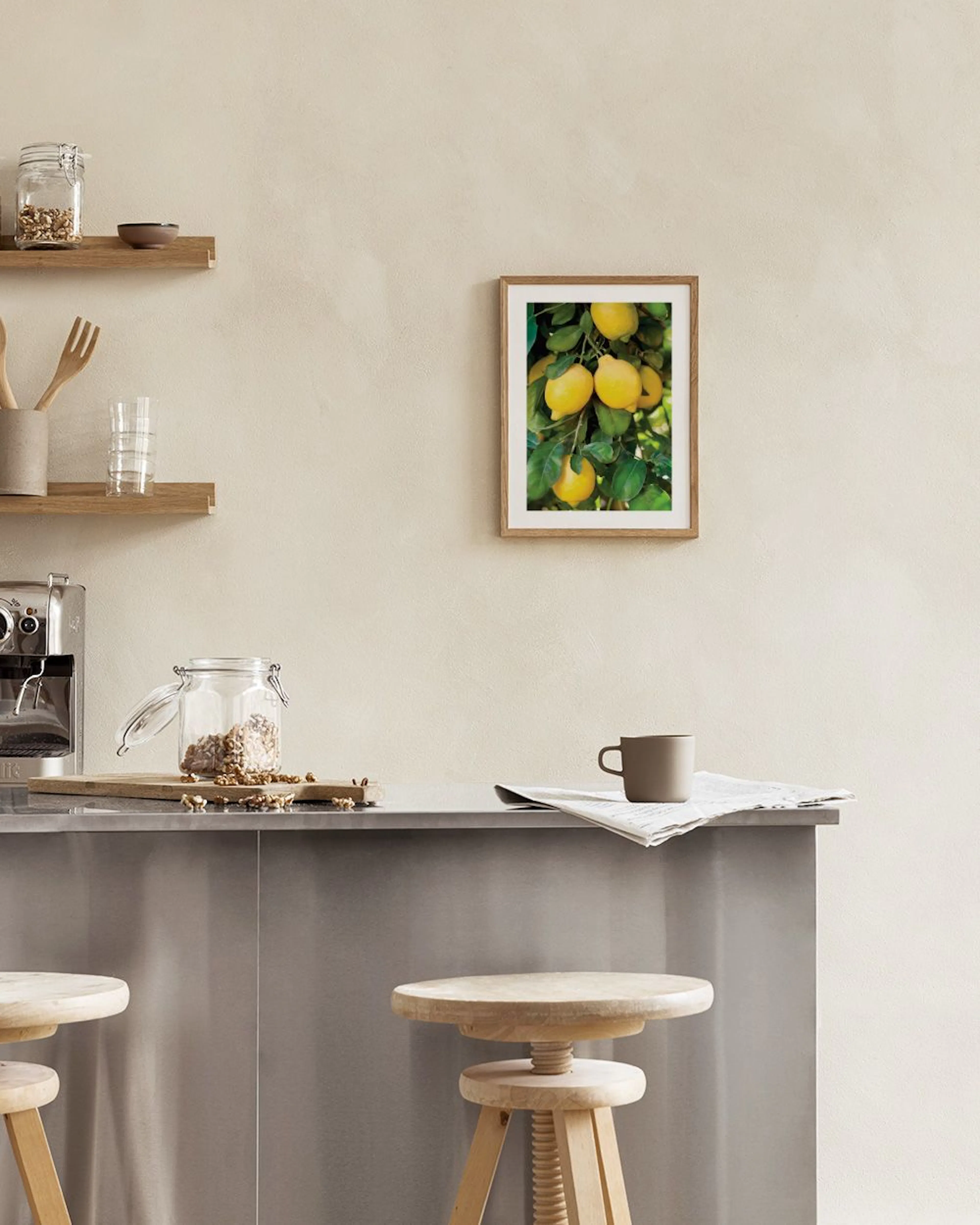 A print of vibrant yellow lemons on a tree branch, hanging above a white console table with a clear vase and open book.