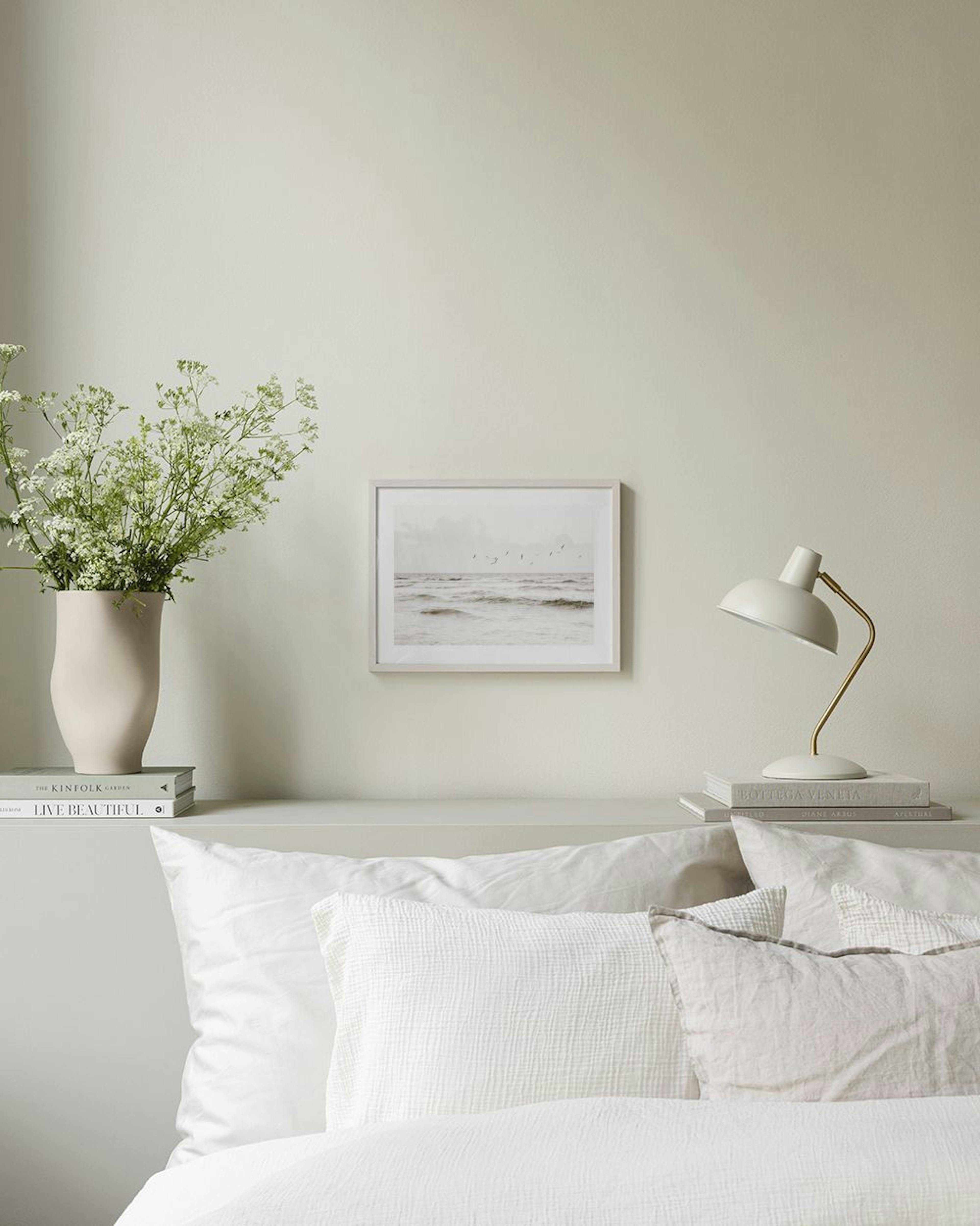 A print of a cloudy ocean with birds, hanging above a gray console table with decorative accents in a modern living room.